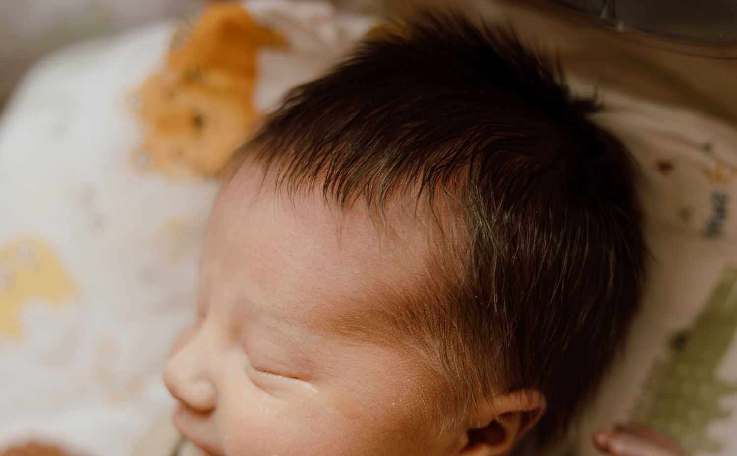 A peaceful sleeping infant rests with closed eyes against a light-colored background.