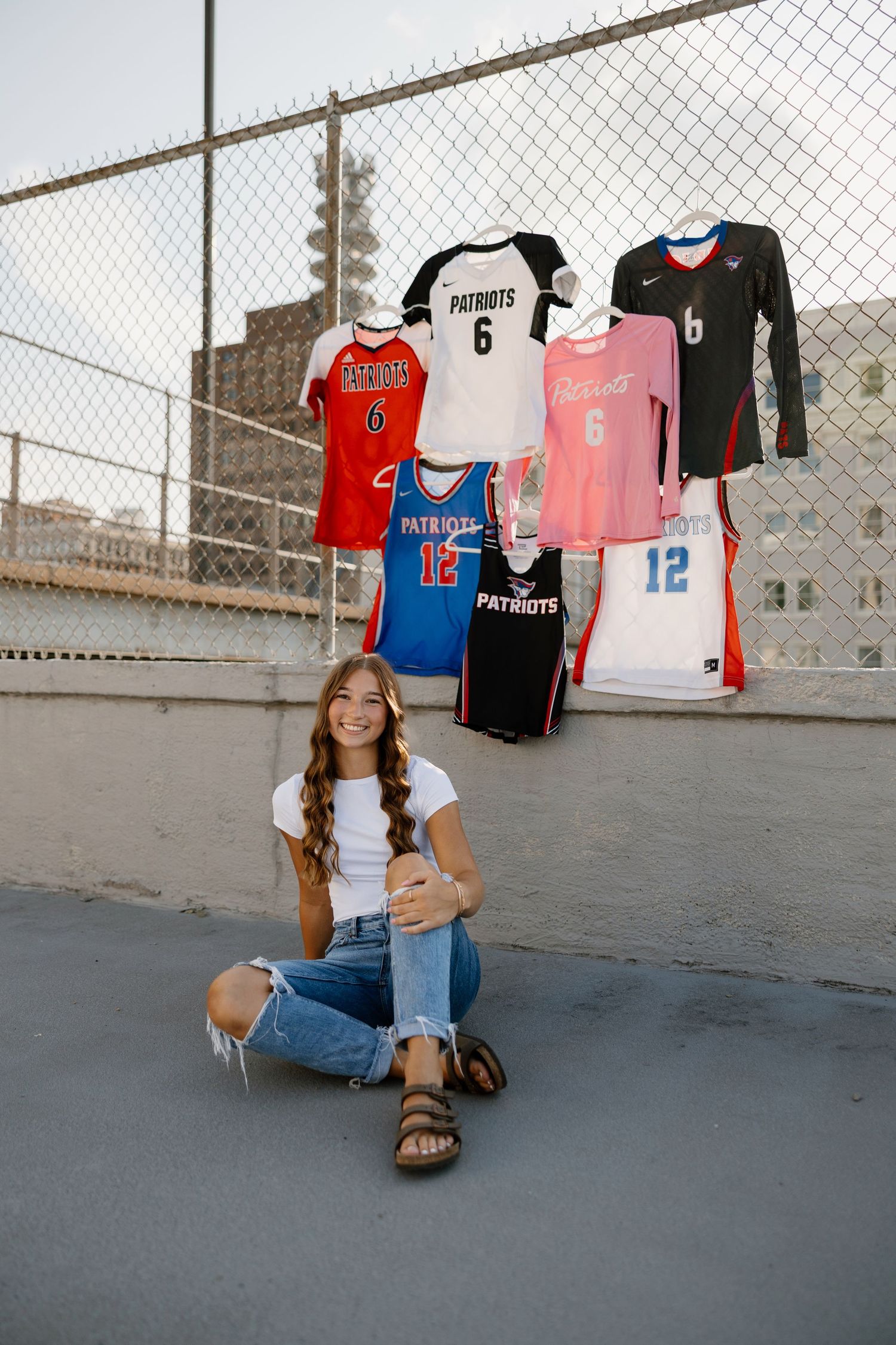 Urban setting with sports jerseys hanging on fence and casual denim outfit.