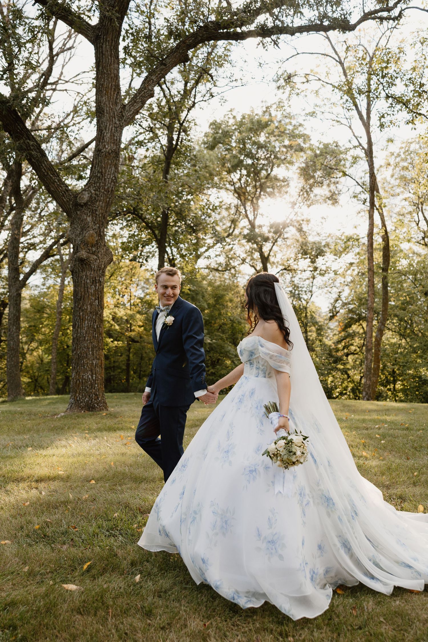Wedding couple dancing in wooded area with bride's dress flowing.