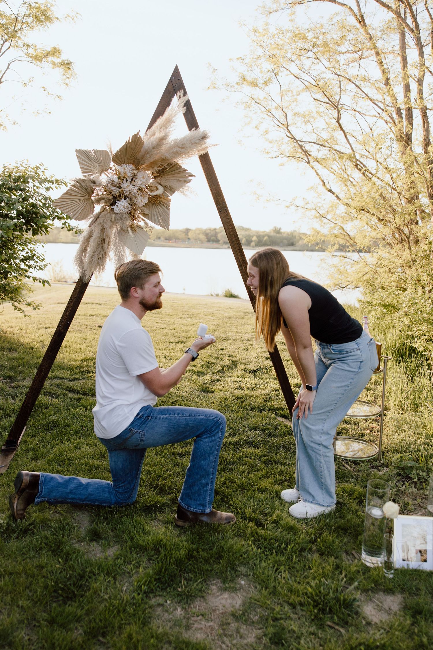 A couple shares a special moment under a decorated arch in a grassy field.