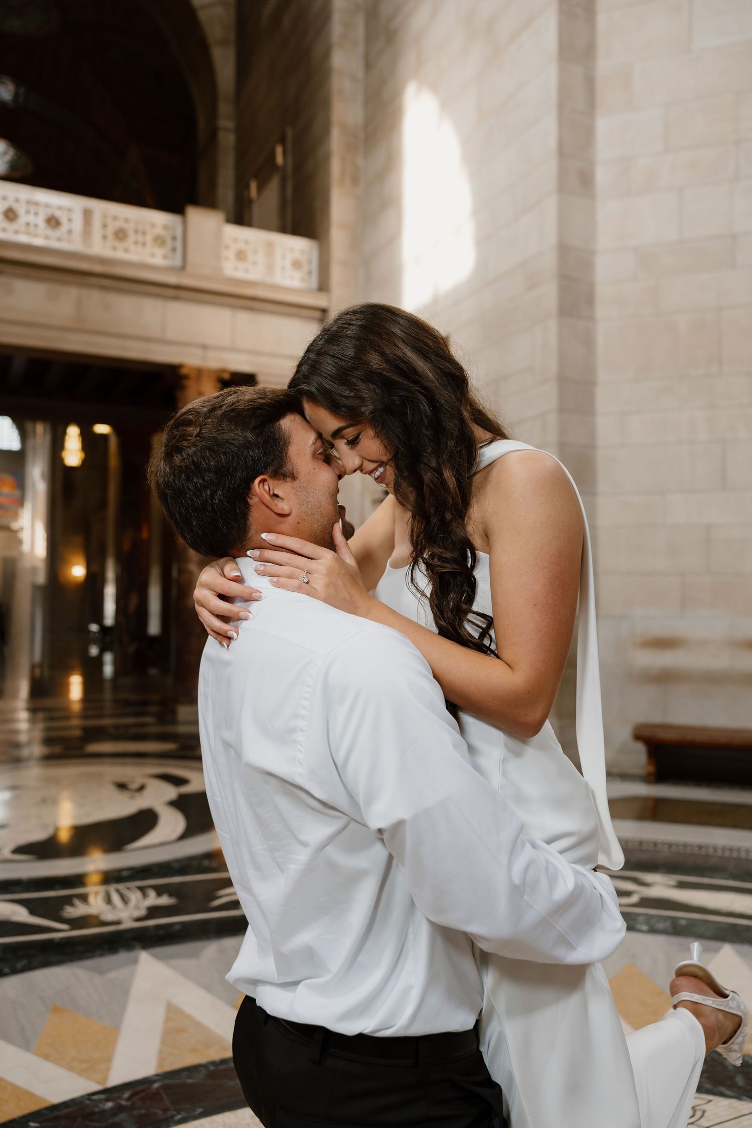 Couple embraces in intimate dance pose inside ornate historic building interior.