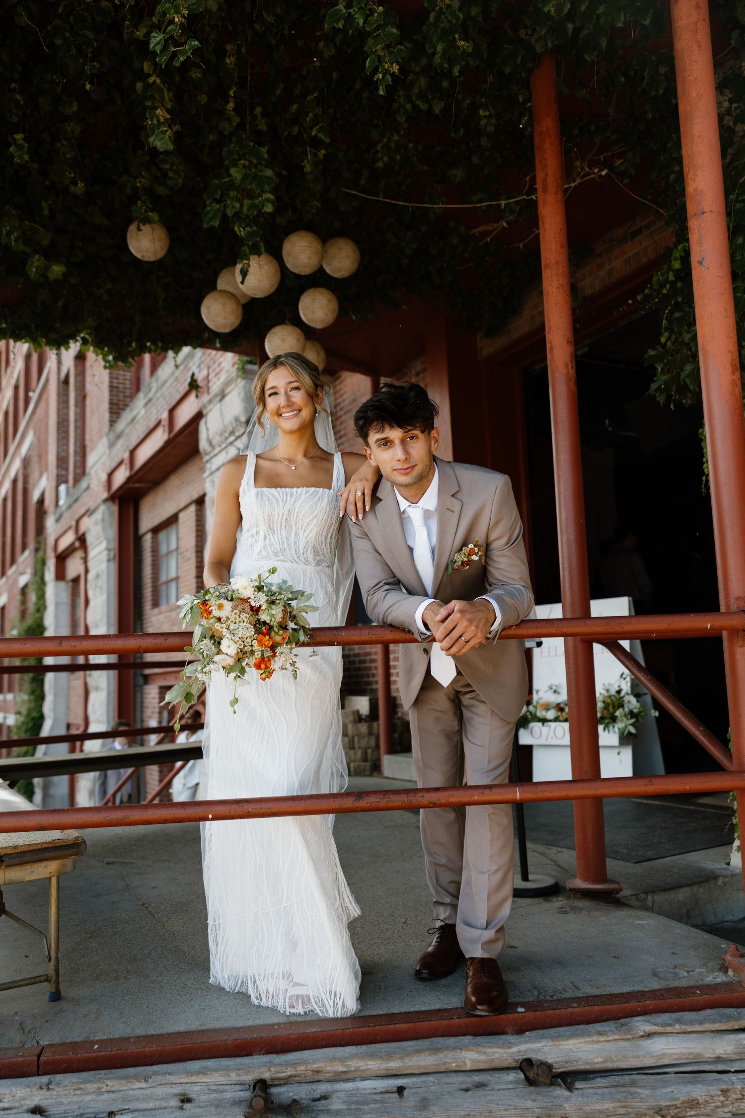 Bride and groom share romantic moments on rustic wooden porch with string lights.