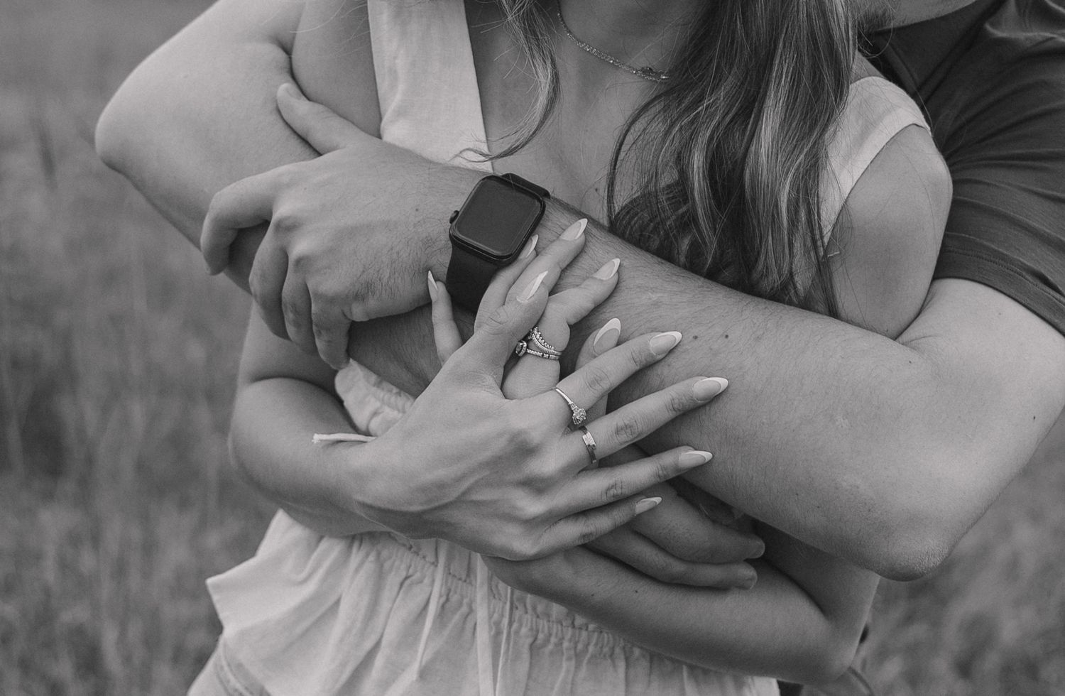 Close-up shot of hands displaying an engagement ring in a natural outdoor setting.