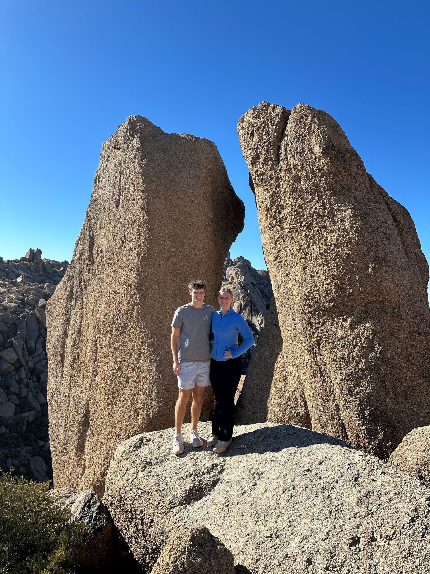 Scenic photos at a rocky mountain formation with tall granite boulders against blue sky.
