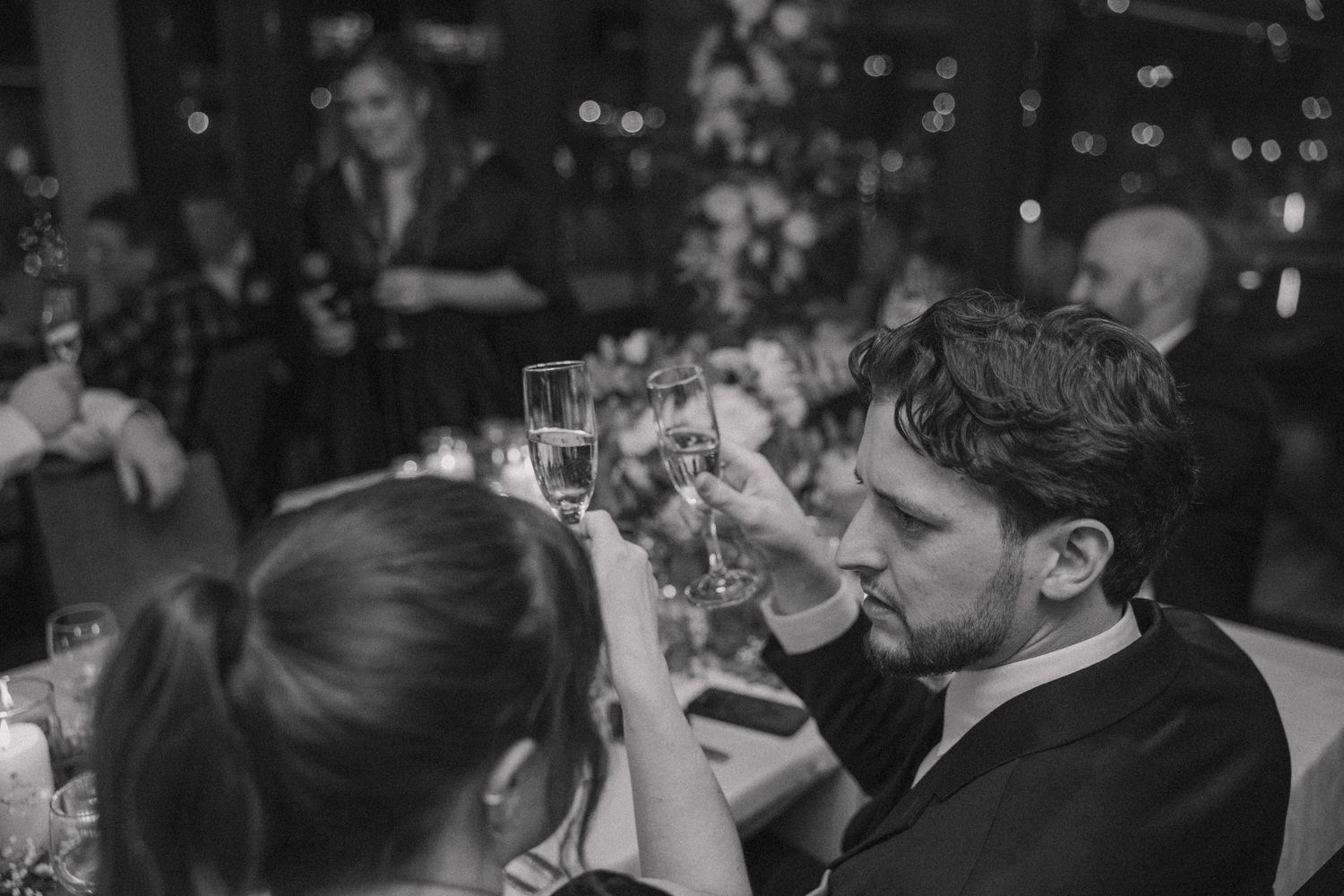 Wedding guests raise glasses in black and white toast during intimate reception celebration.