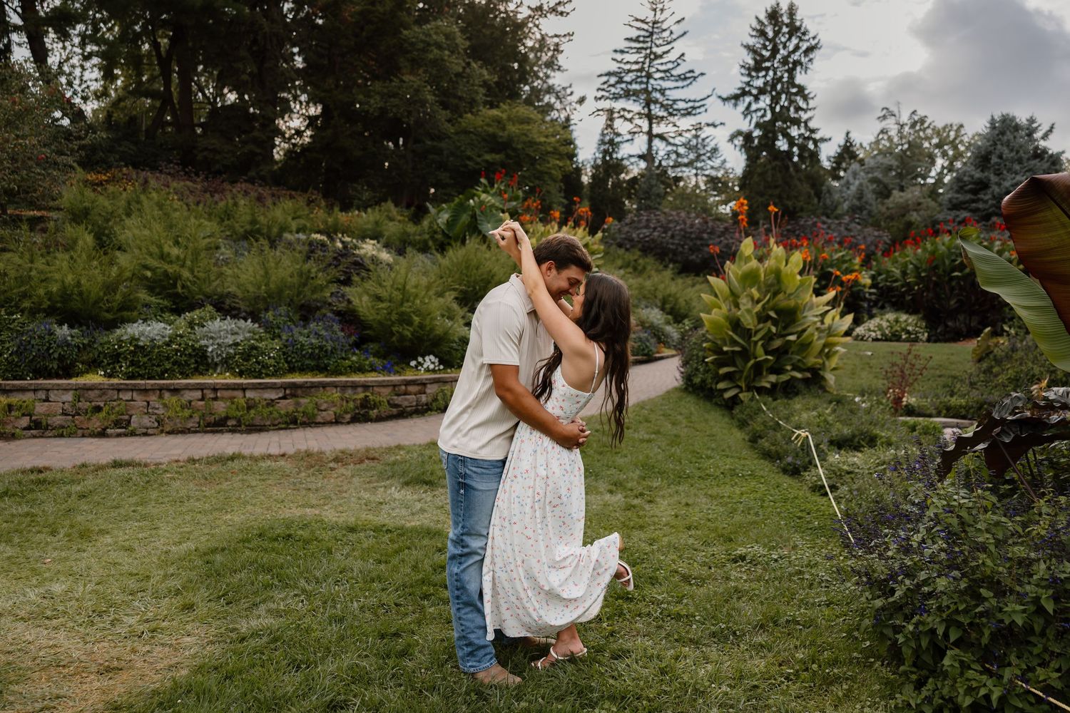 A couple poses together in a lush garden setting during golden hour.