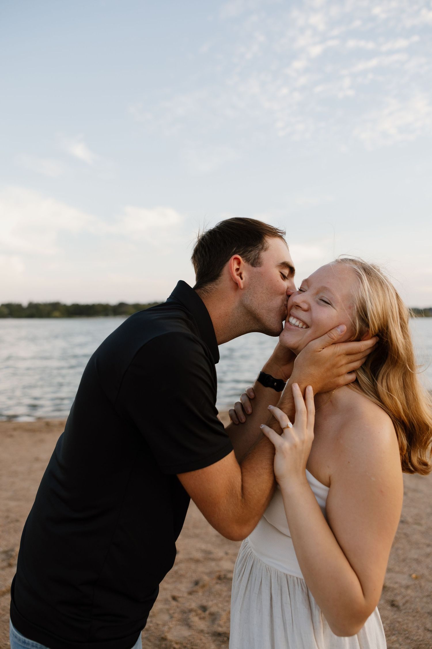 Romantic couple sharing intimate moments and kisses on a beach at sunset.