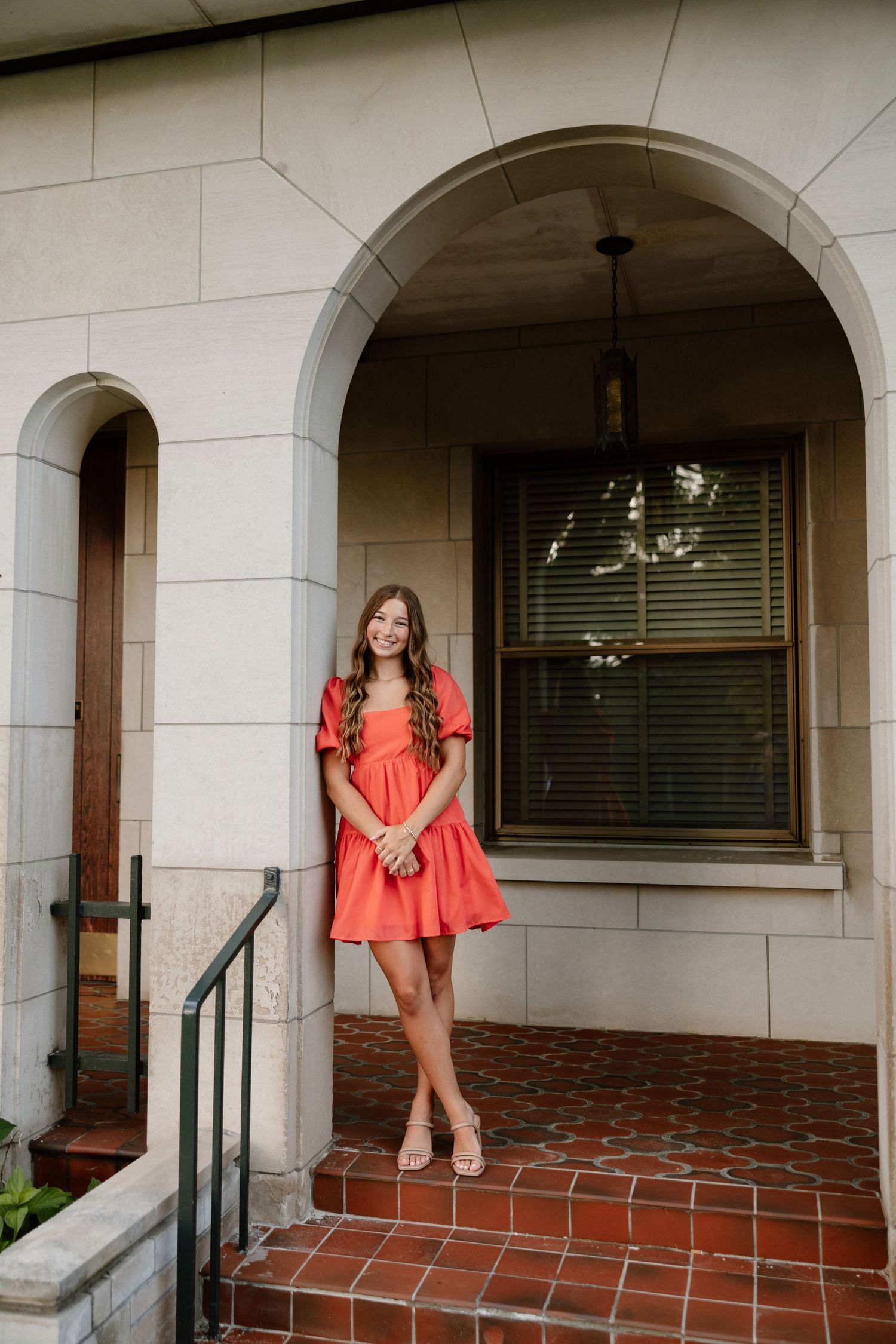 Outdoor portrait session on a covered porch with brick and stone architectural details.