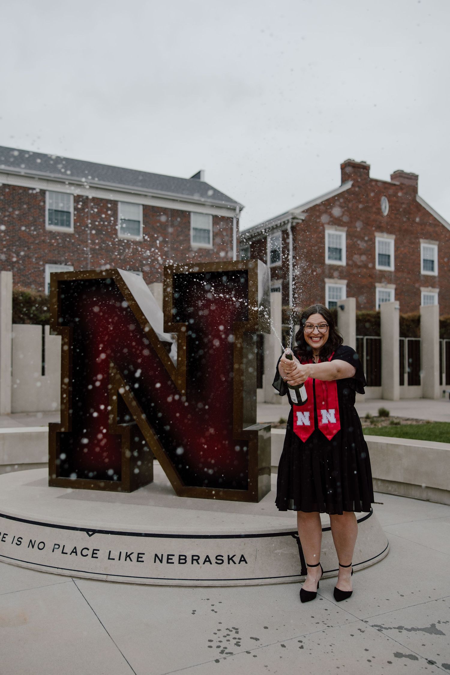Large 'NEBRASKA' letters display with festive lights against brick buildings.