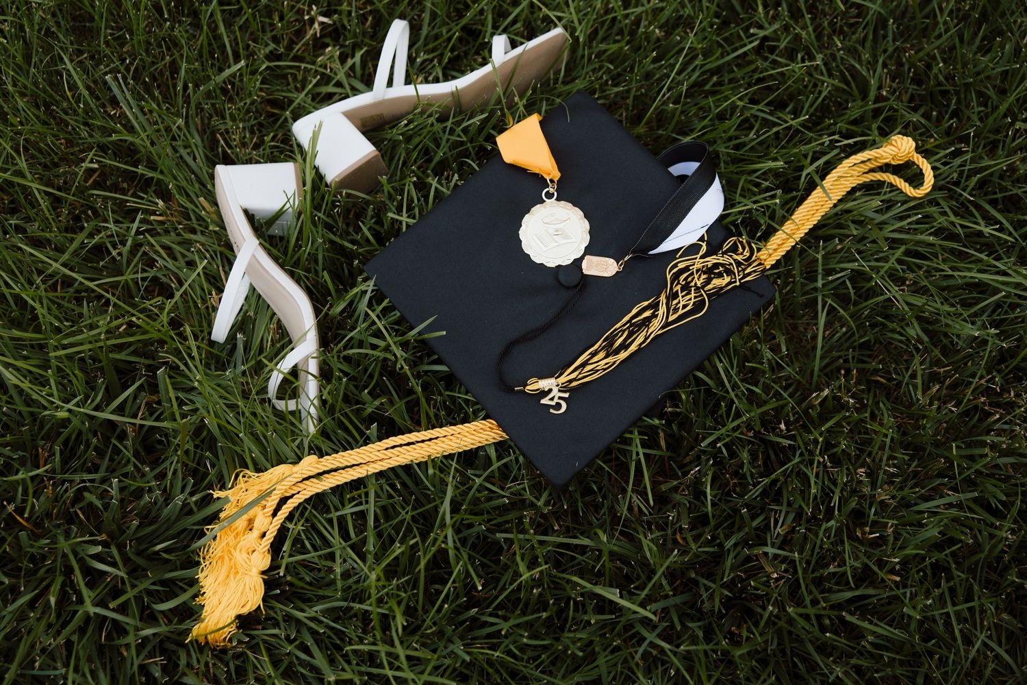 Graduation caps and tassels arranged on green grass background.
