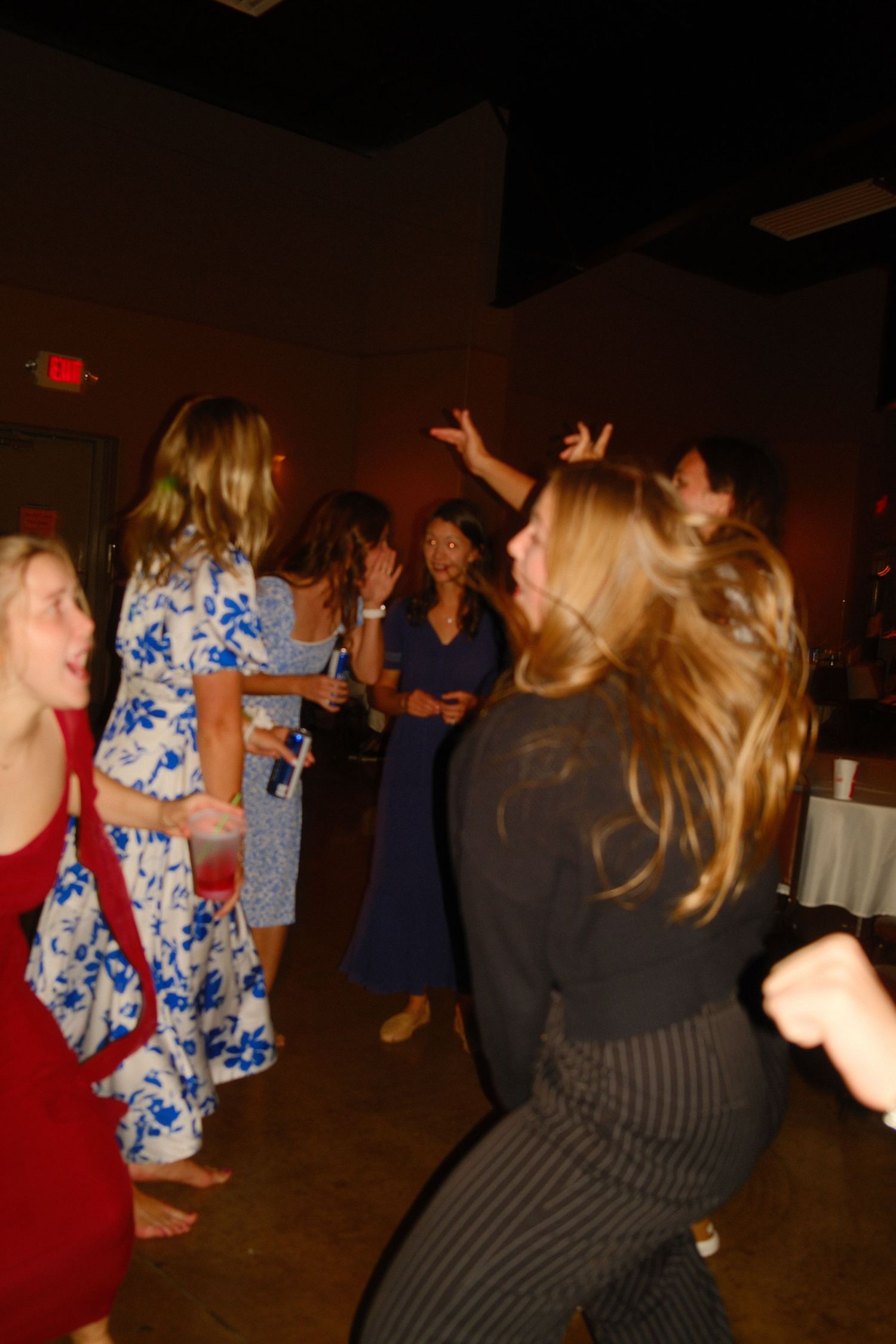 People dancing together in a dimly lit room at what appears to be a party or celebration event.