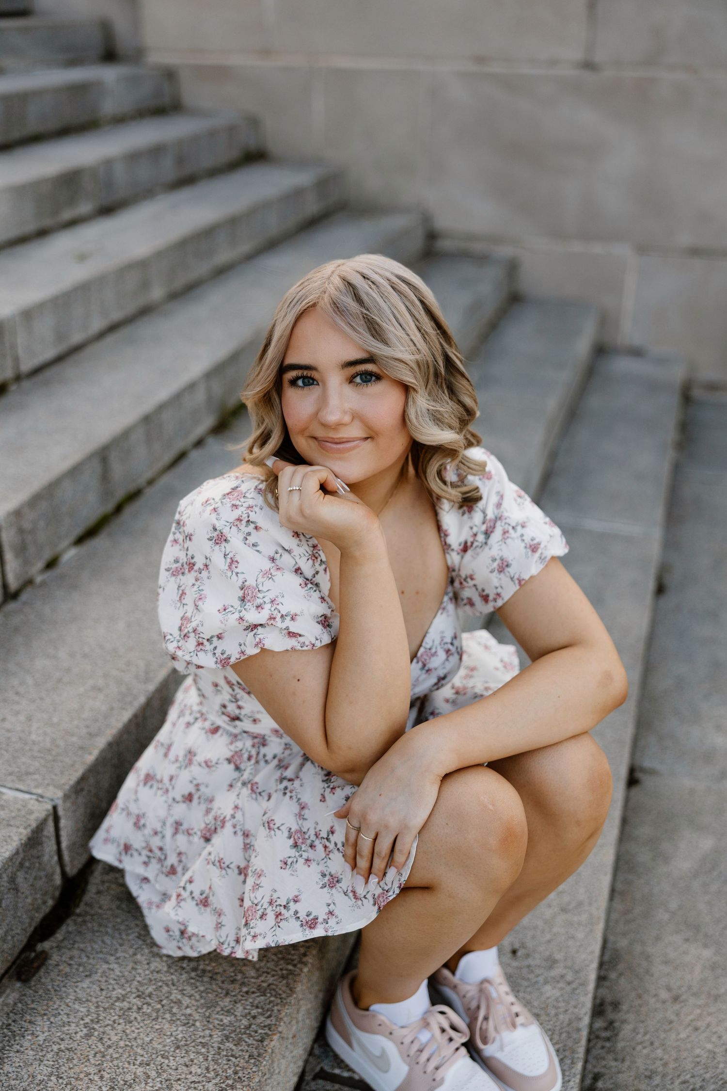 Portrait session on concrete steps with floral dress and casual styling.