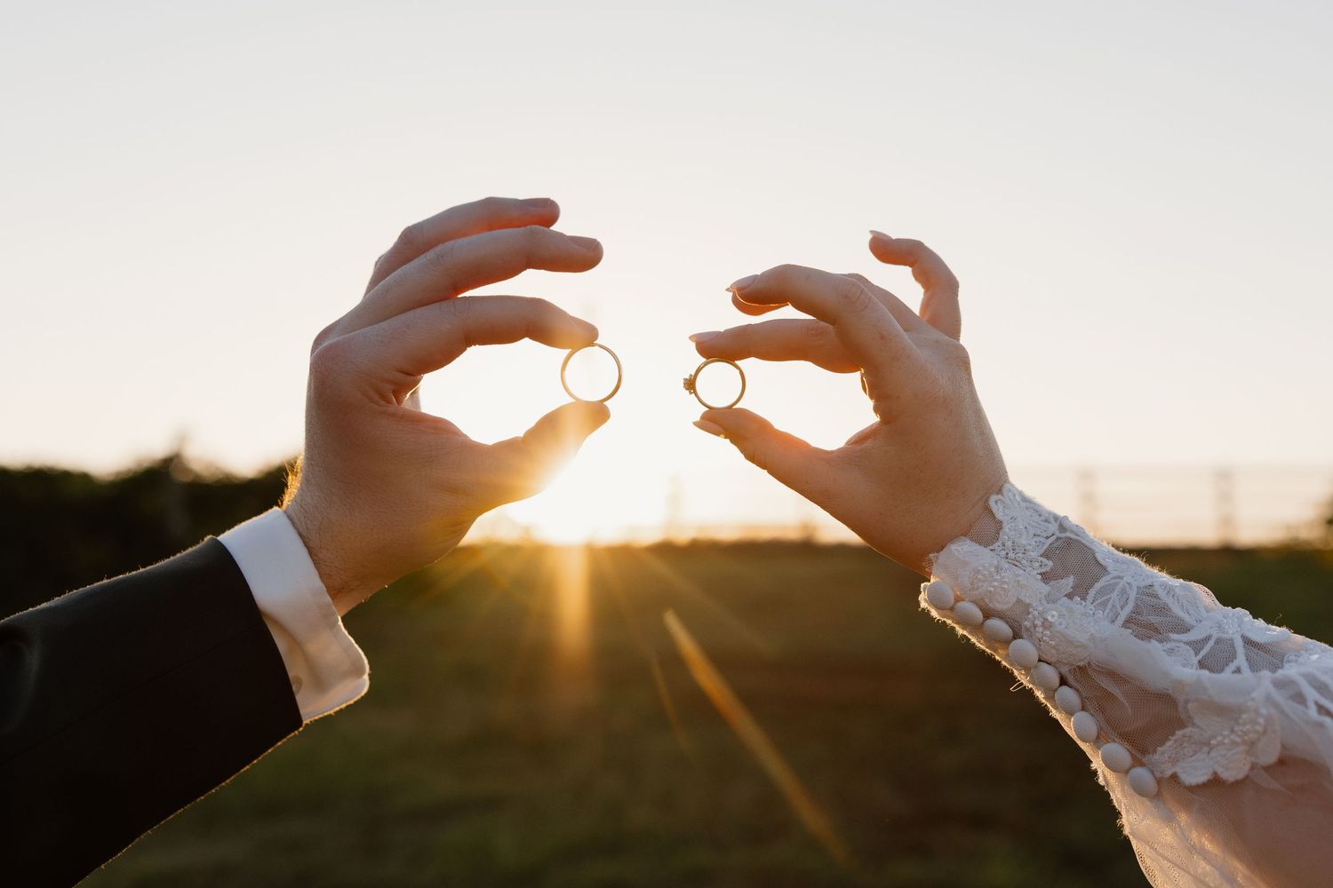 Wedding rings silhouetted against golden sunset sky.