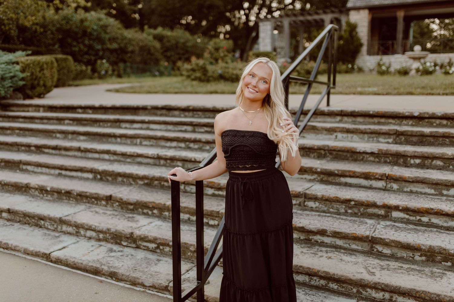 An elegant portrait on stone steps wearing a black dress at golden hour.