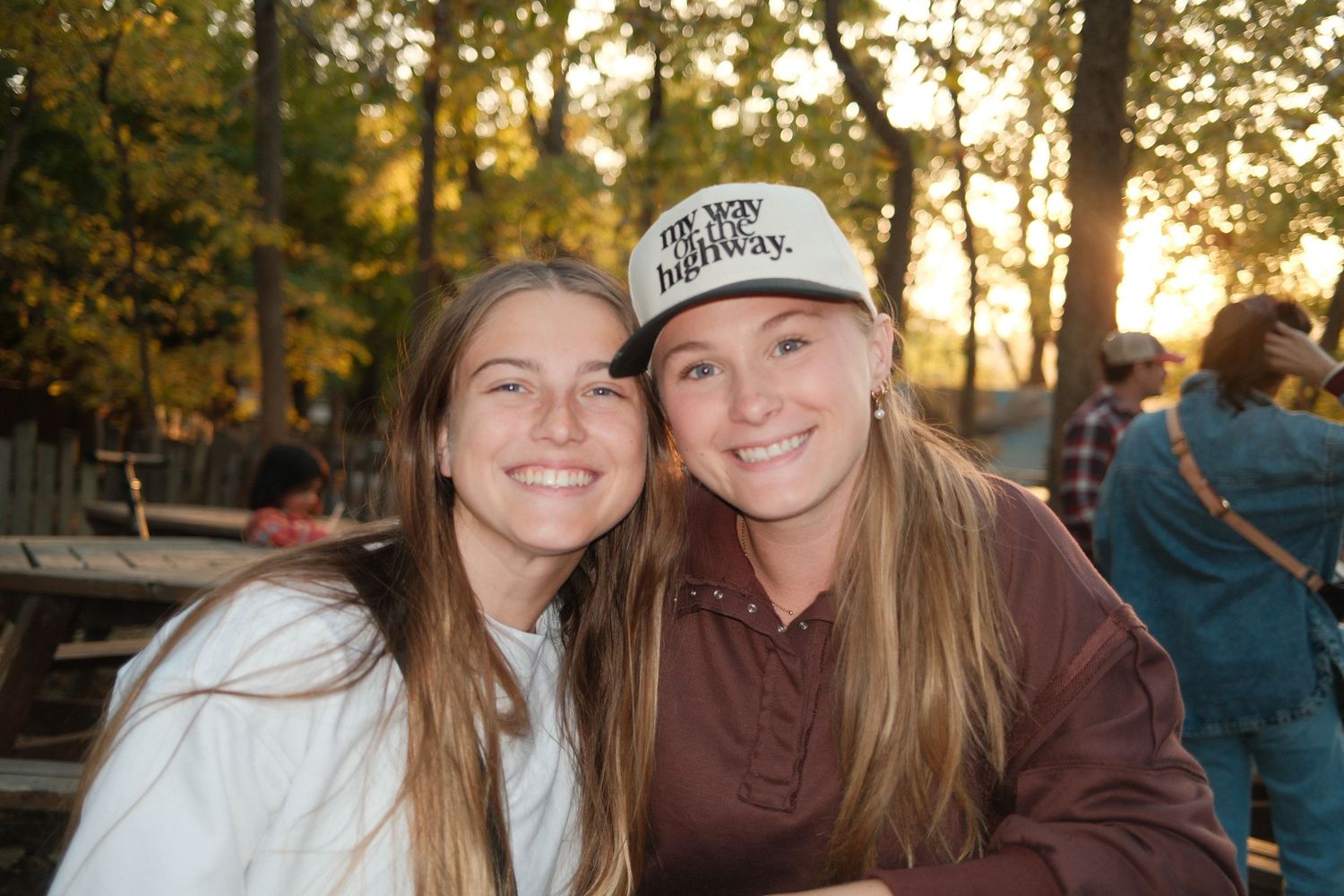 A casual outdoor gathering at sunset with autumn foliage in the background.