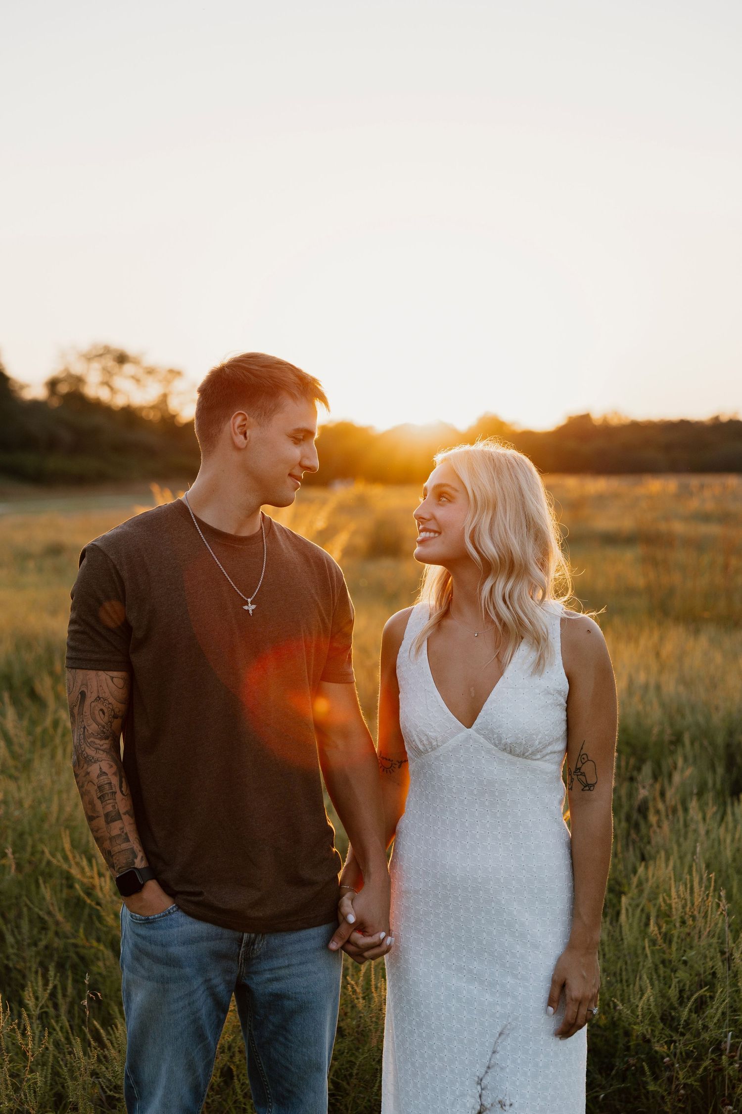 A couple shares intimate moments in a field during golden hour sunset.