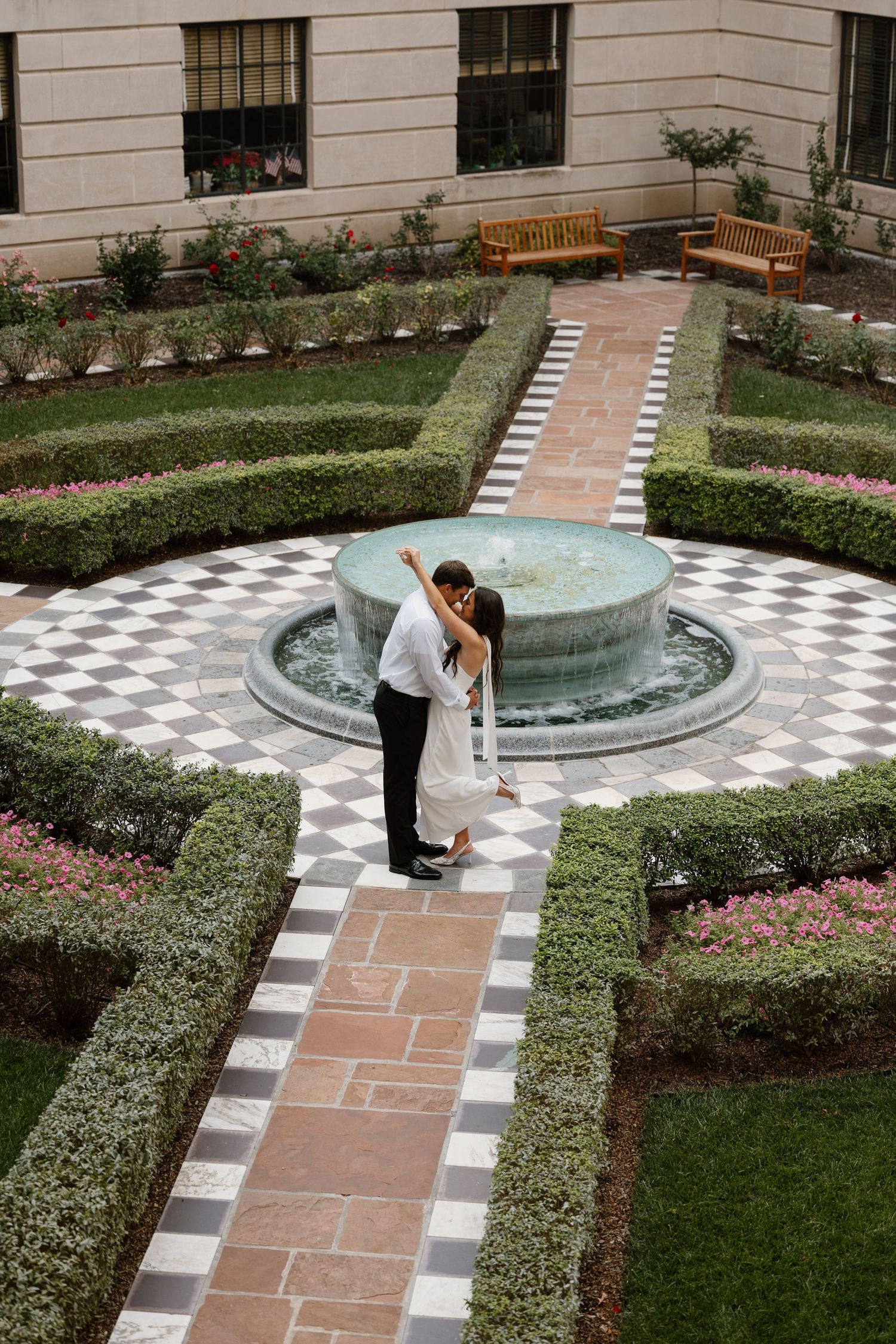 Formal garden with checkered pathway leading to circular fountain.