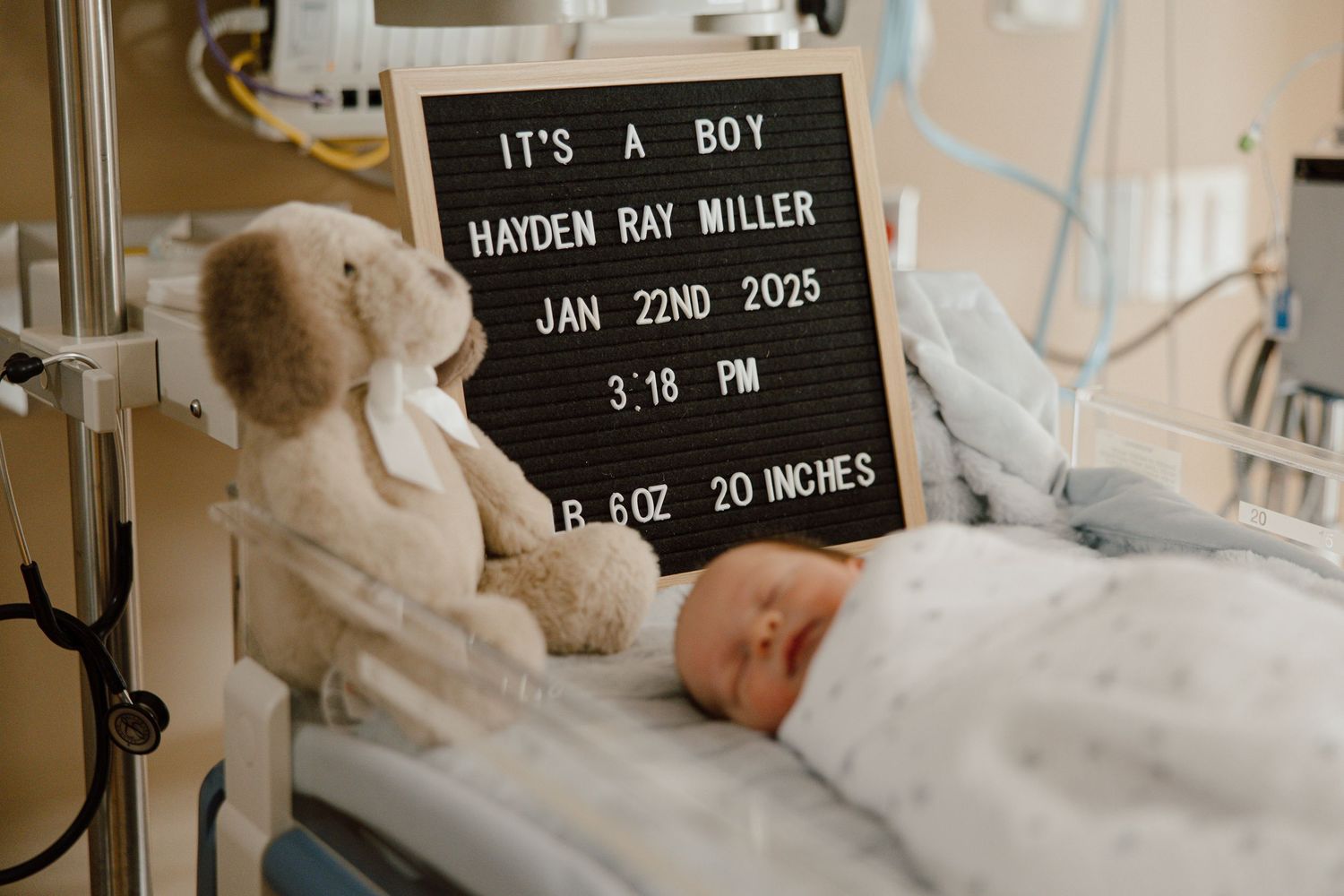 Hospital letterboard announcing baby details with newborn in background.
