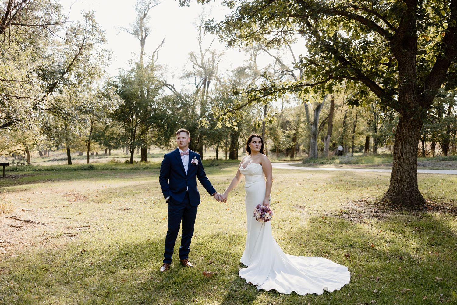 Wedding couple poses for romantic portraits in a scenic outdoor park setting.