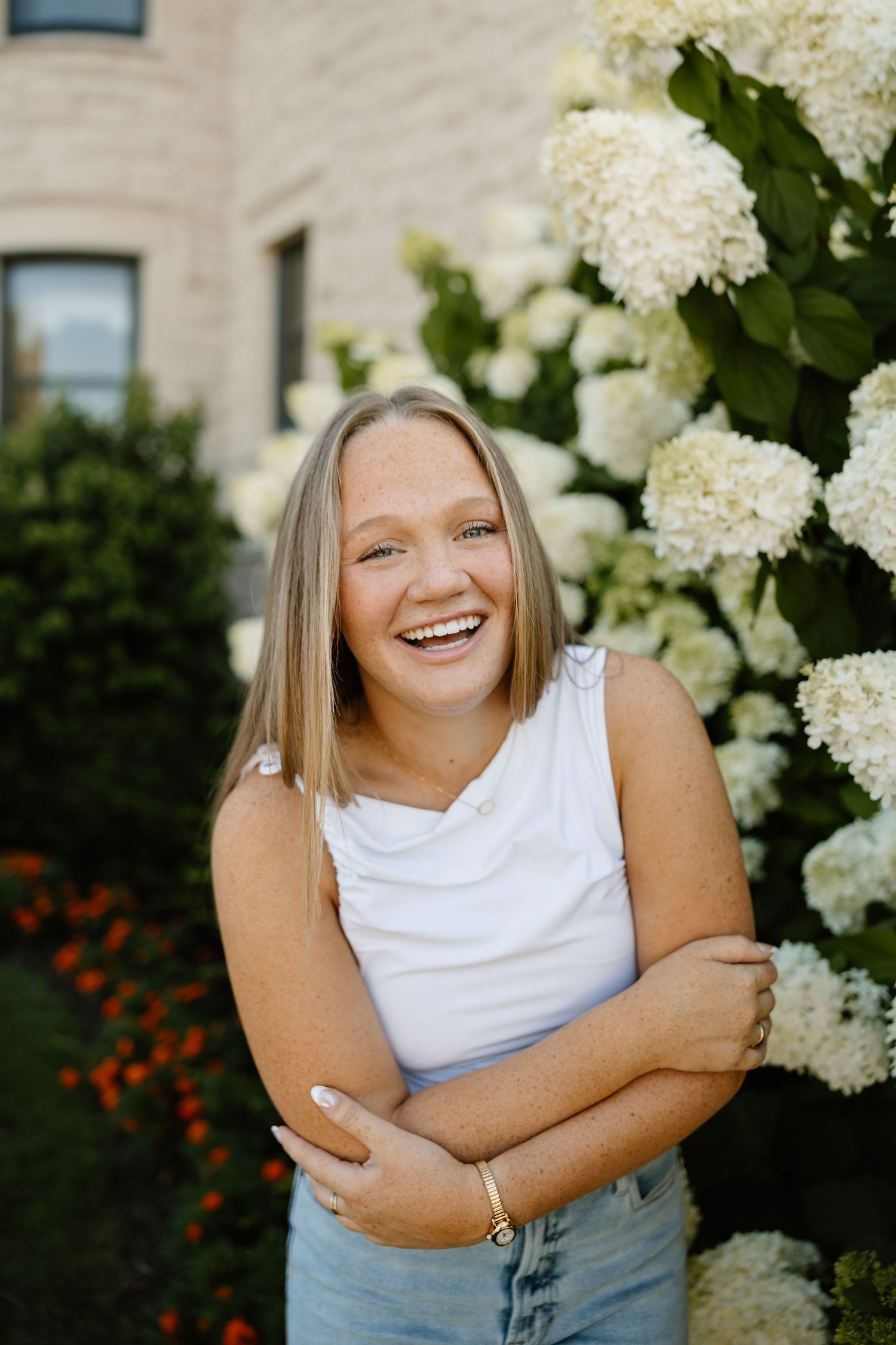 Casual outdoor photoshoot with white hydrangea flowers in background.