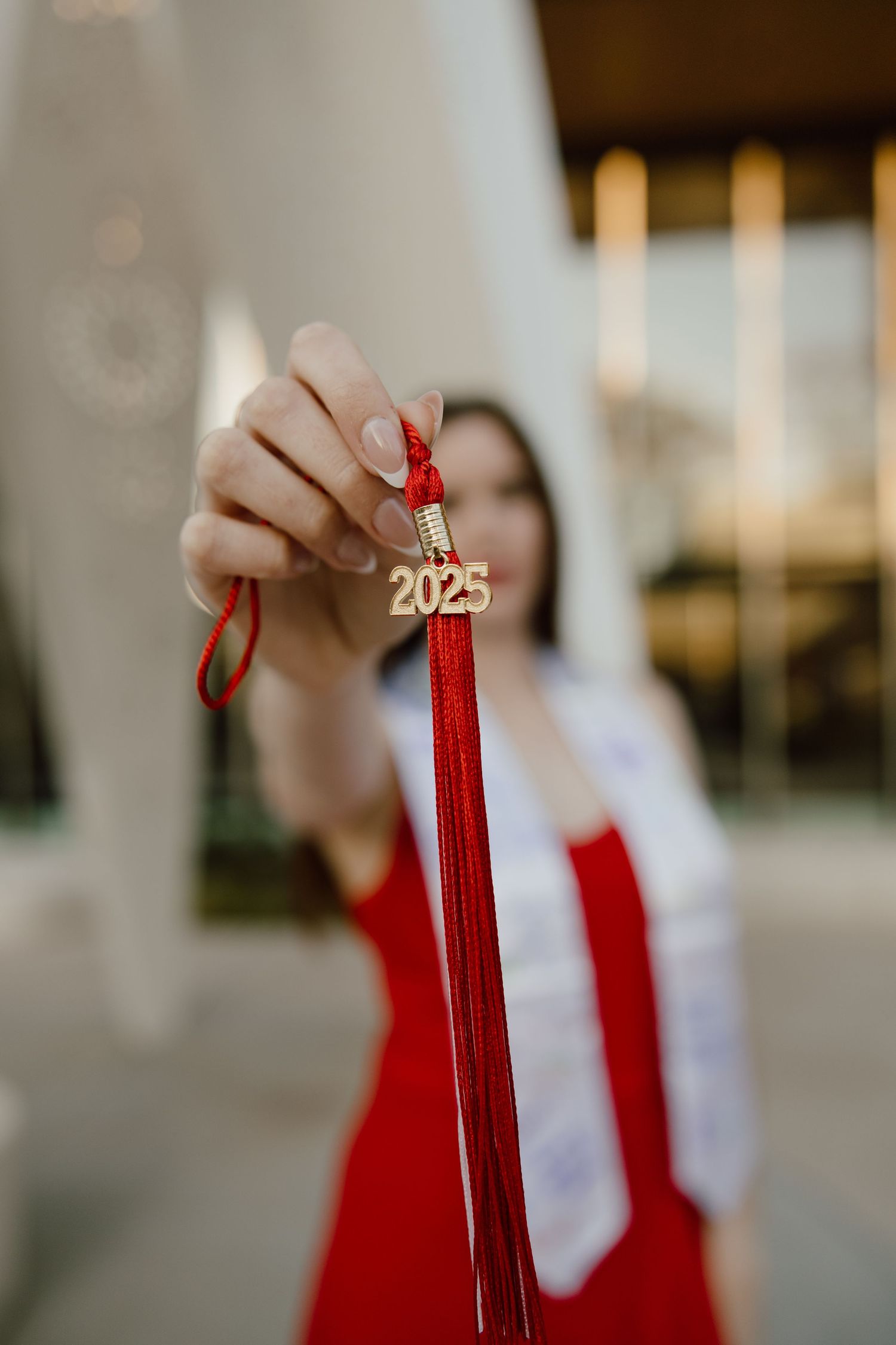 Close-up shots of graduation tassels in bright red against a blurred background.