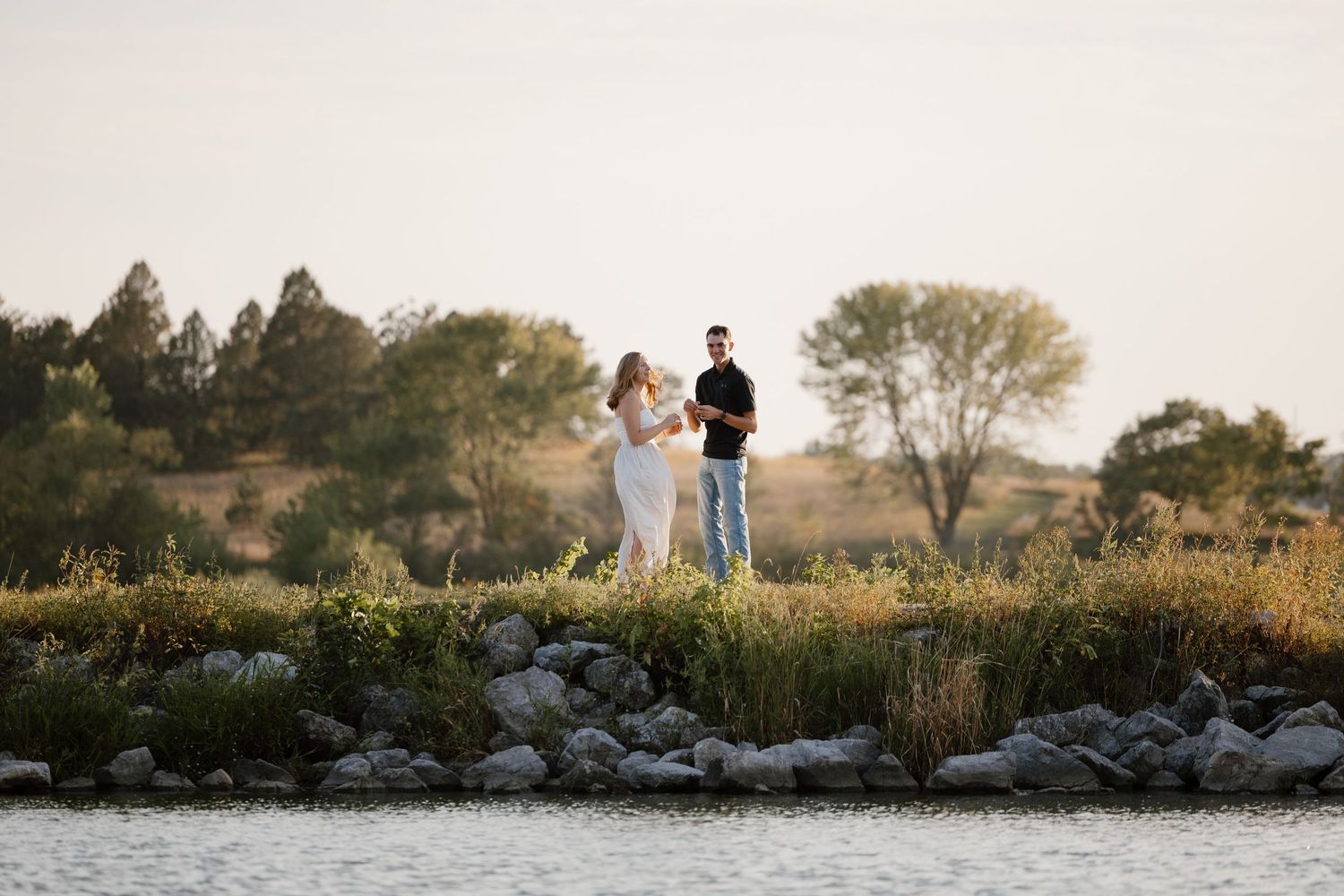 Panoramic view of a couple's proposal moment on a rocky overlook at sunset.