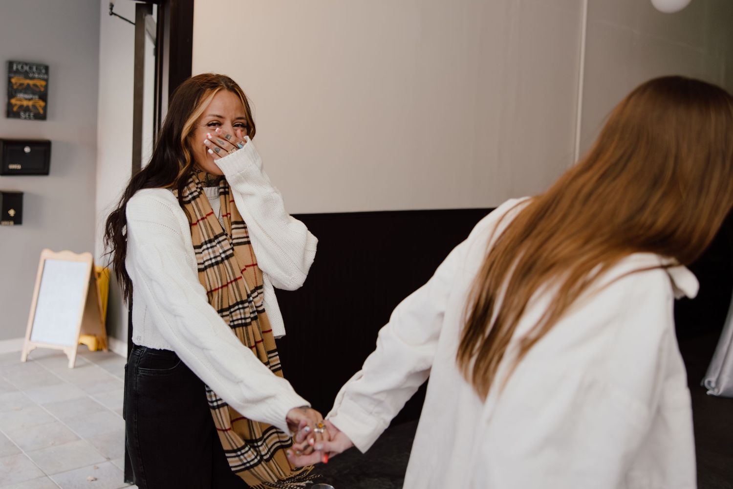 Two girls in white sweaters share an emotional moment during a celebration.