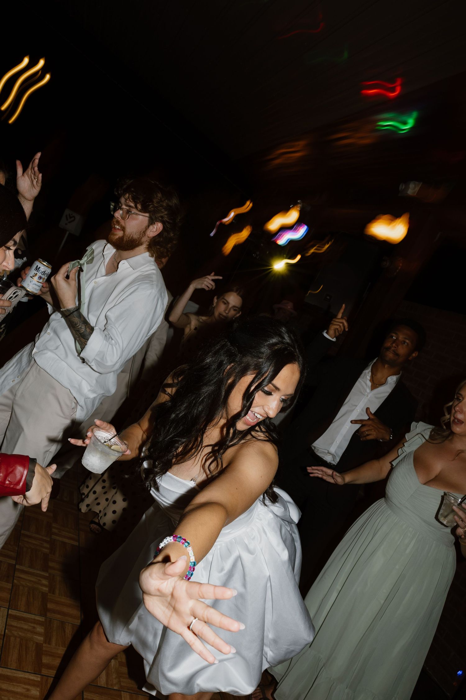 Wedding reception dance party with colorful lights and guests dancing.
