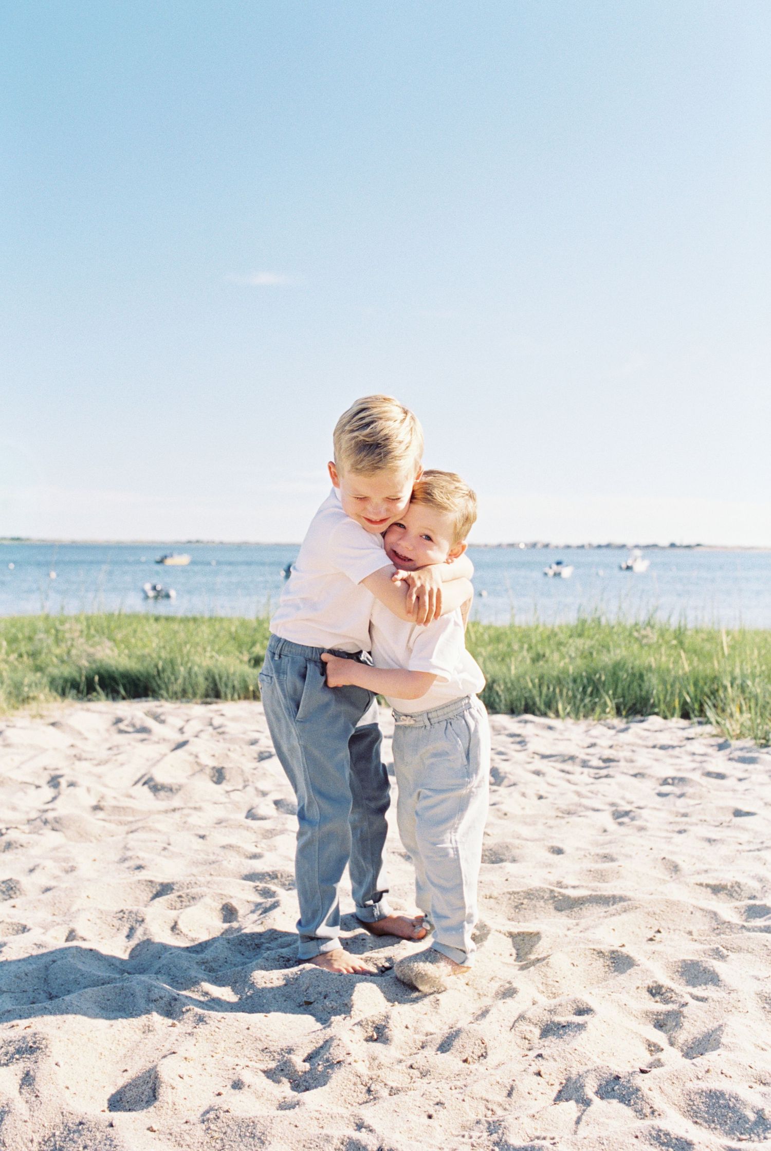 Intimate family moments shared on a sandy beach with ocean and marsh grass in background.