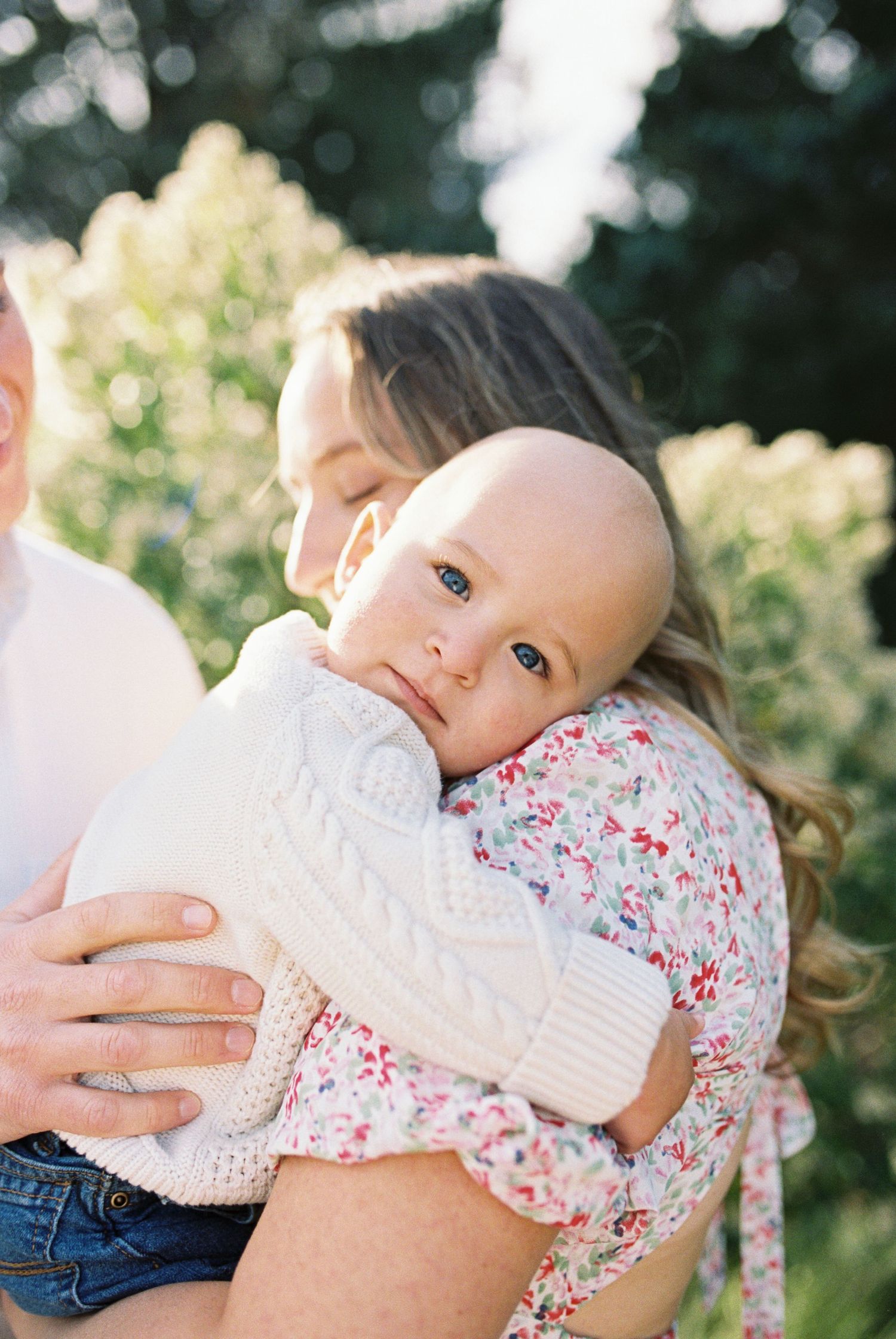 Sweet moments between a baby and parent captured in a garden setting.