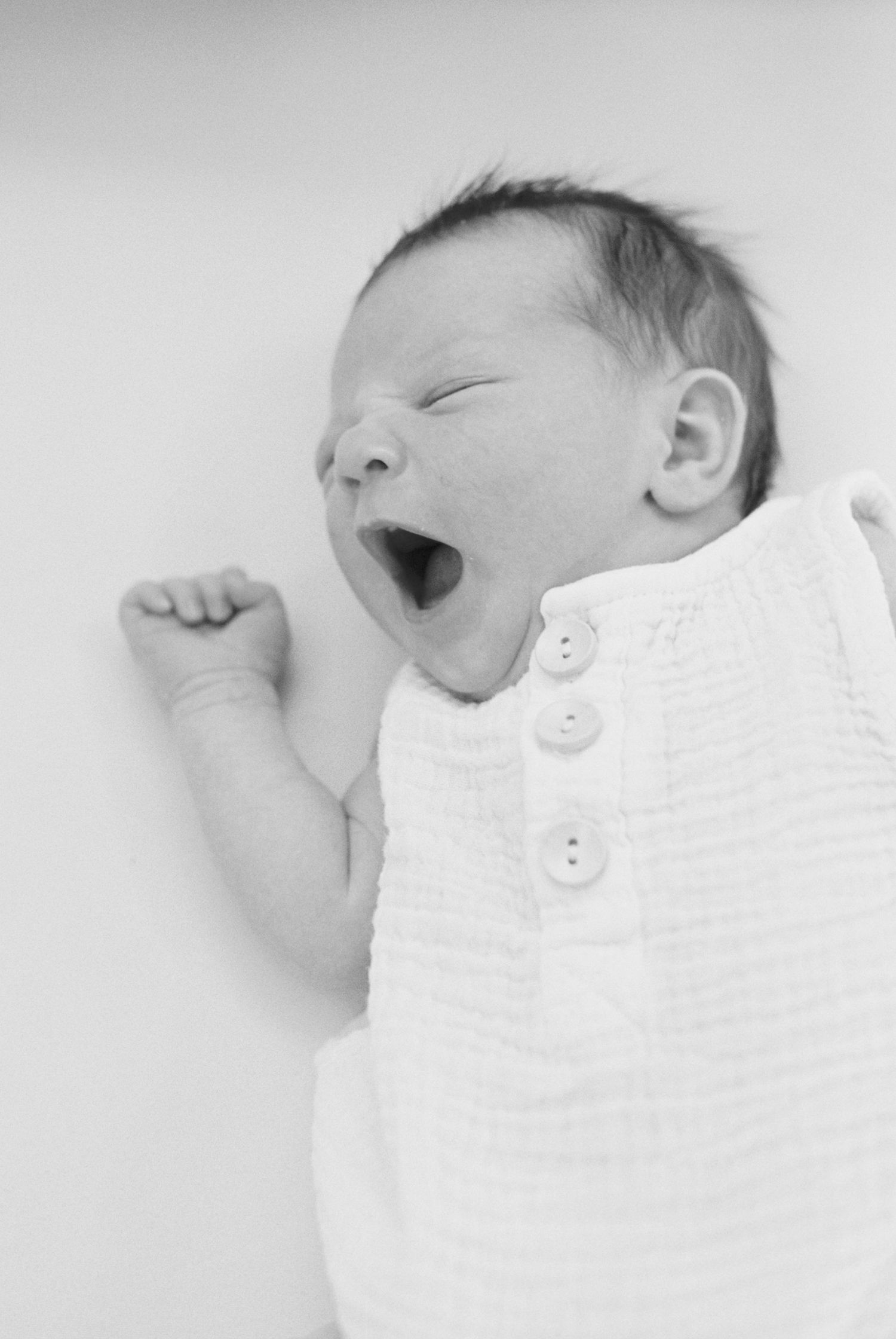 Series of black and white photos showing newborn baby in white clothing.