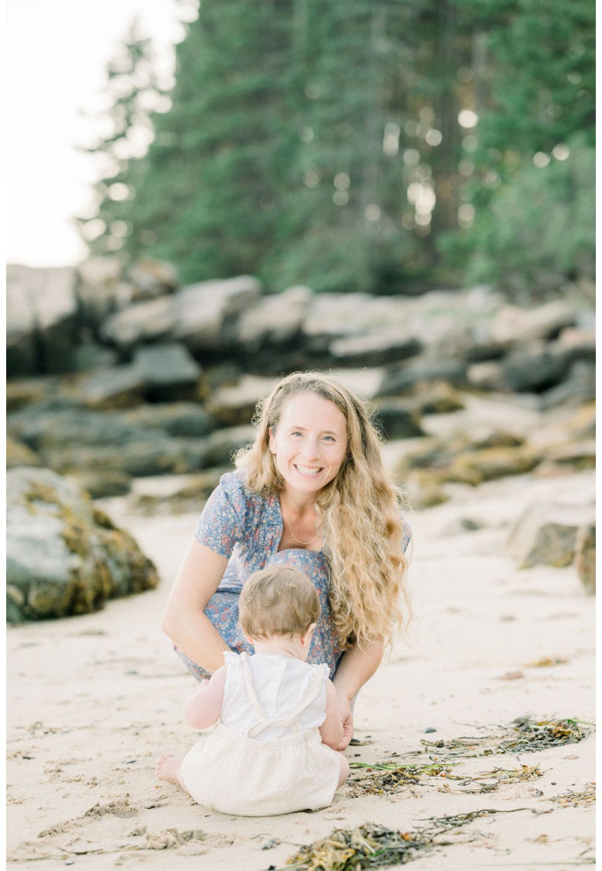 A tender interaction on a scenic beach with evergreen forest and rocky shoreline in the background.