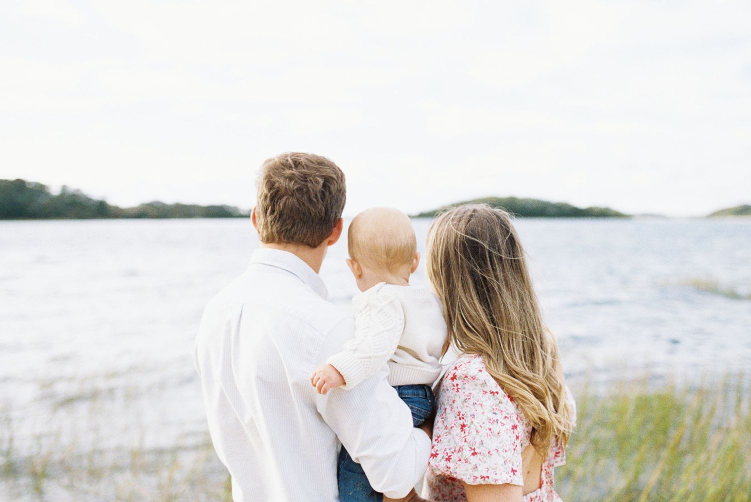 Family walking together along a sandy beach shoreline.