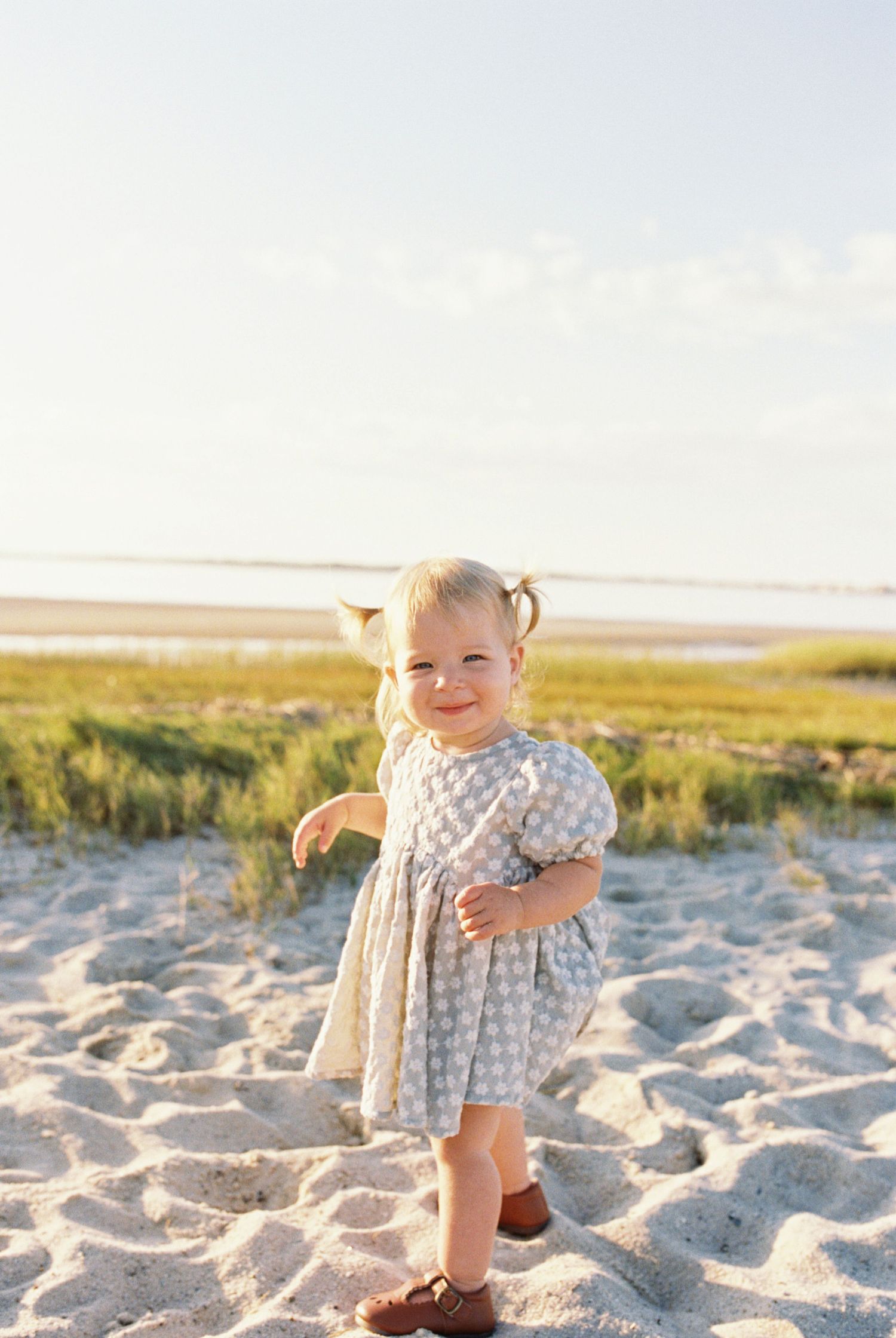 A series of photos showing a small child playing on a sandy beach during golden hour.