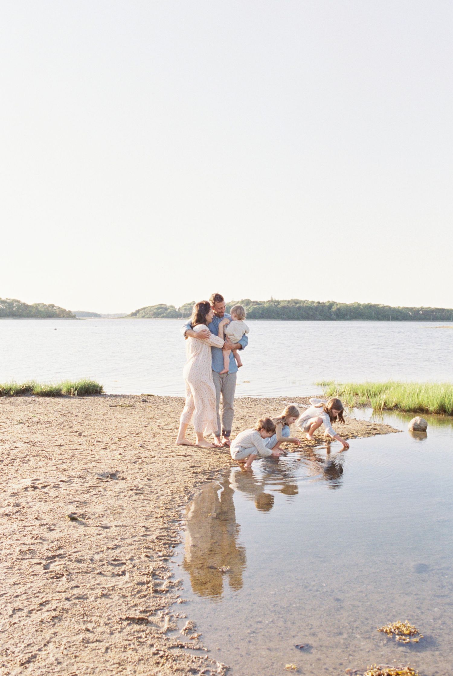 Family enjoying time together at the water's edge on a rocky beach.