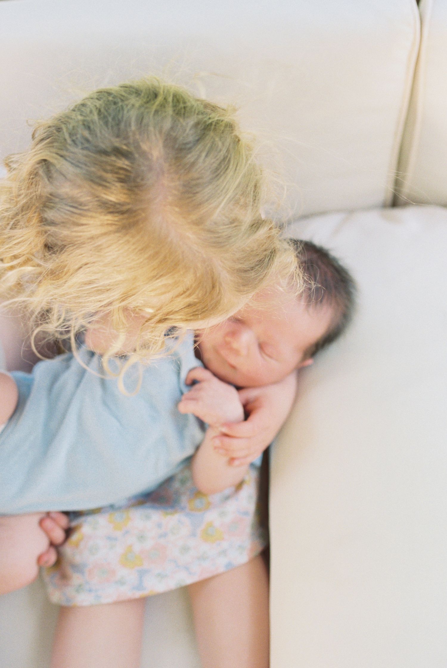 Baby wearing light blue shirt rests peacefully on floral patterned fabric.