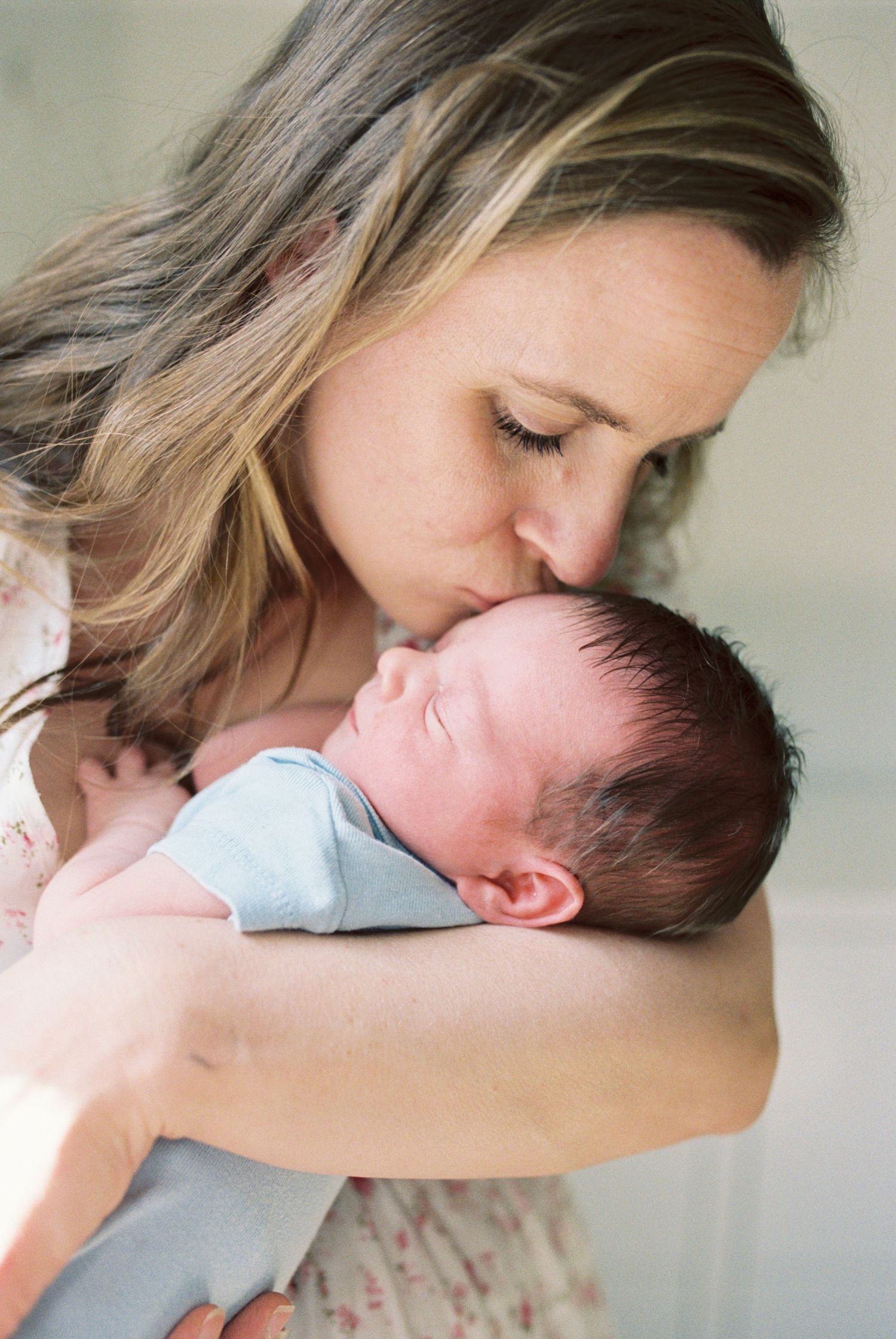 An intimate portrait of maternal love as mother kisses newborn's head.