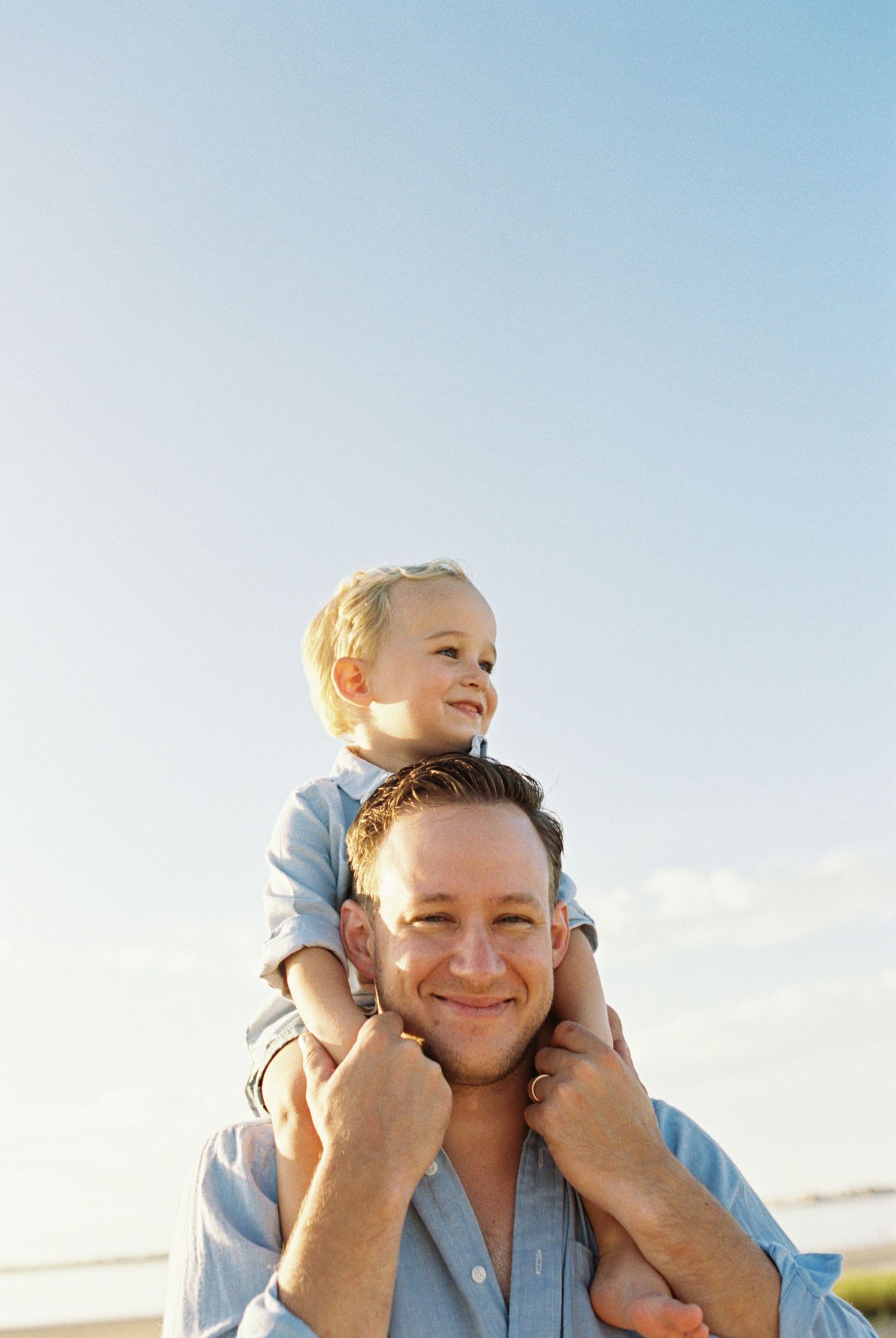 Joyful moment between parent and child playing on shoulders at the beach.