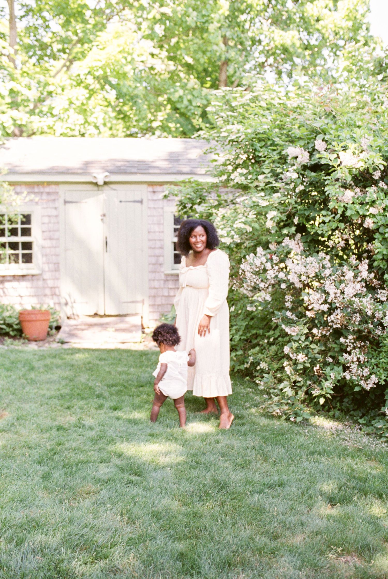 Family playtime captured in a lush garden with white flowering bushes.