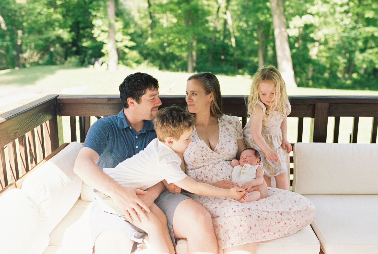 Family of four sharing joyful moment together on outdoor porch.