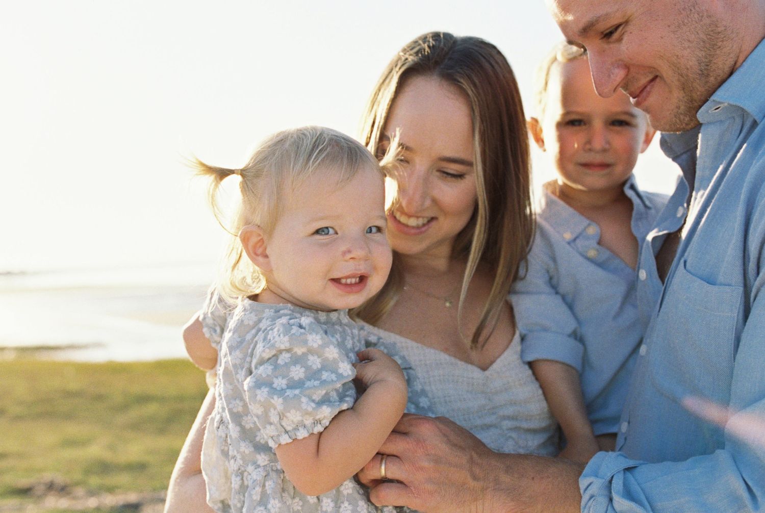 Intimate family portraits captured during golden hour with coastal scenery in the background.