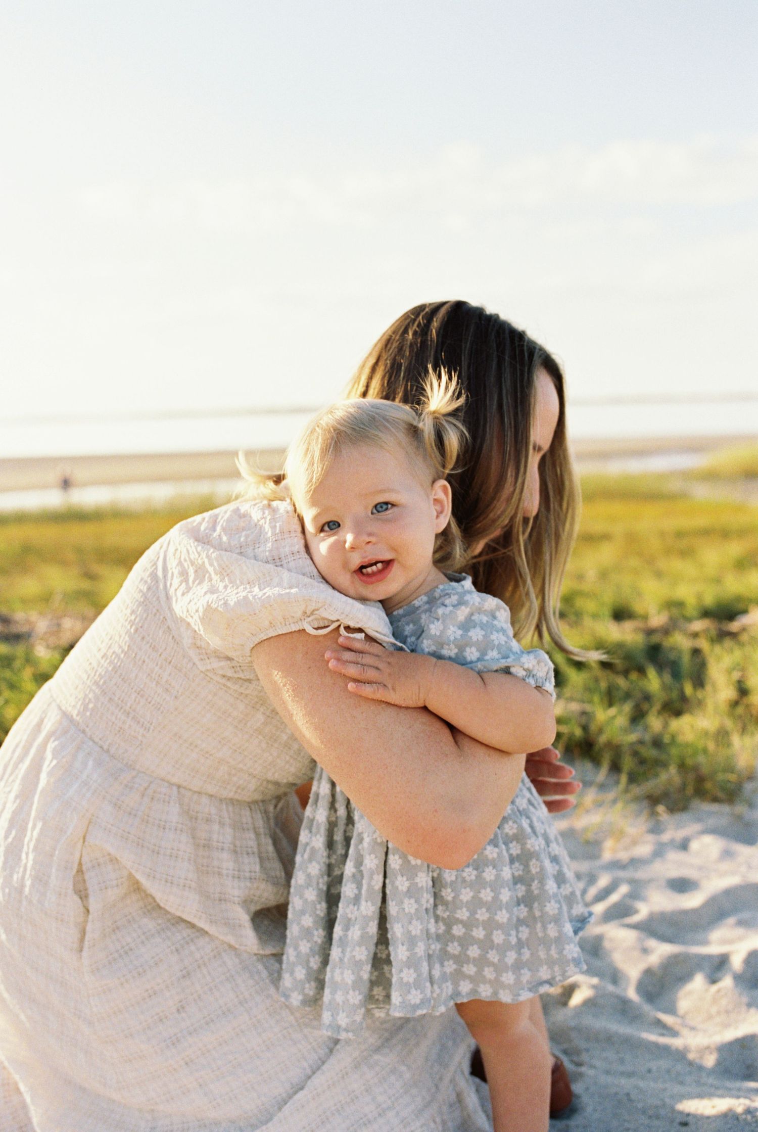 Sweet embrace between parent and child on sandy beach during sunset.