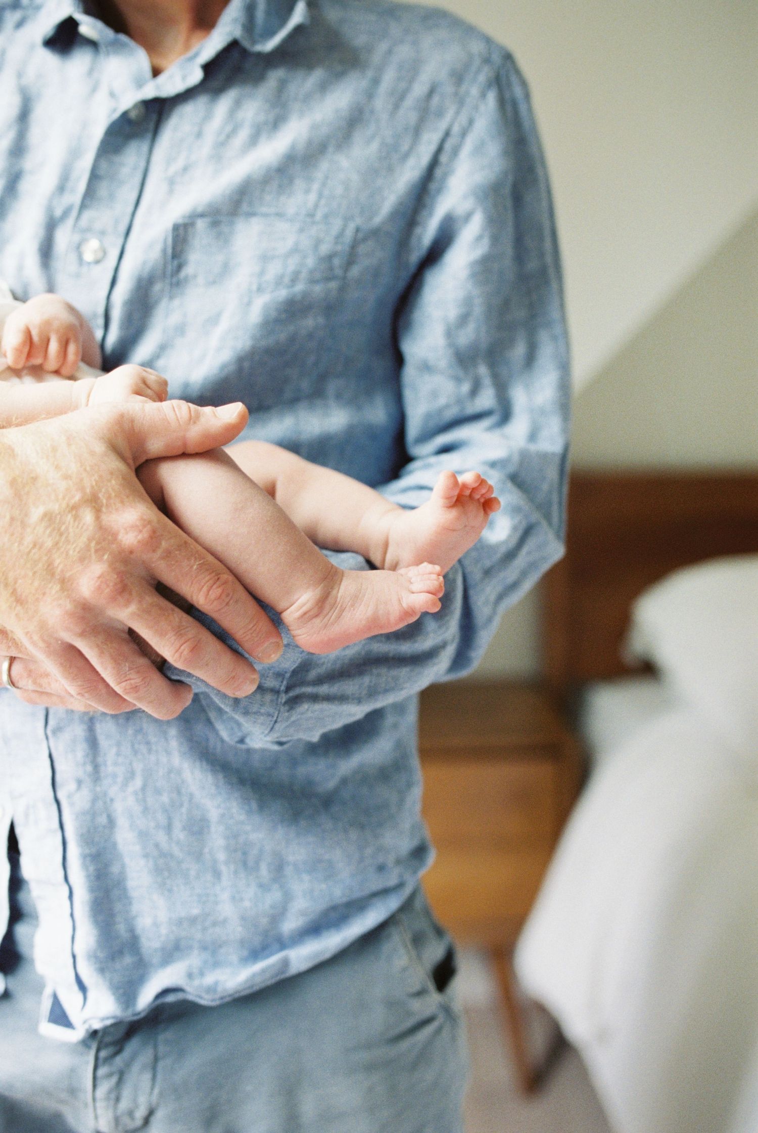 Close-up series of gentle hands holding tiny newborn feet indoors.