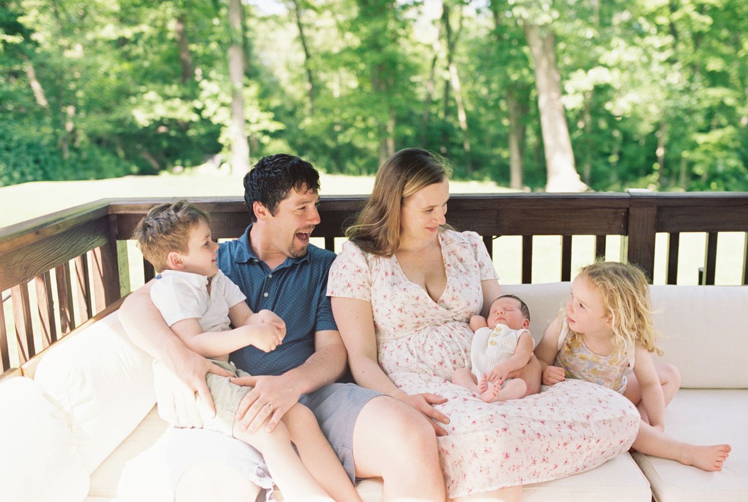 Happy family relaxing together on outdoor porch sofa.