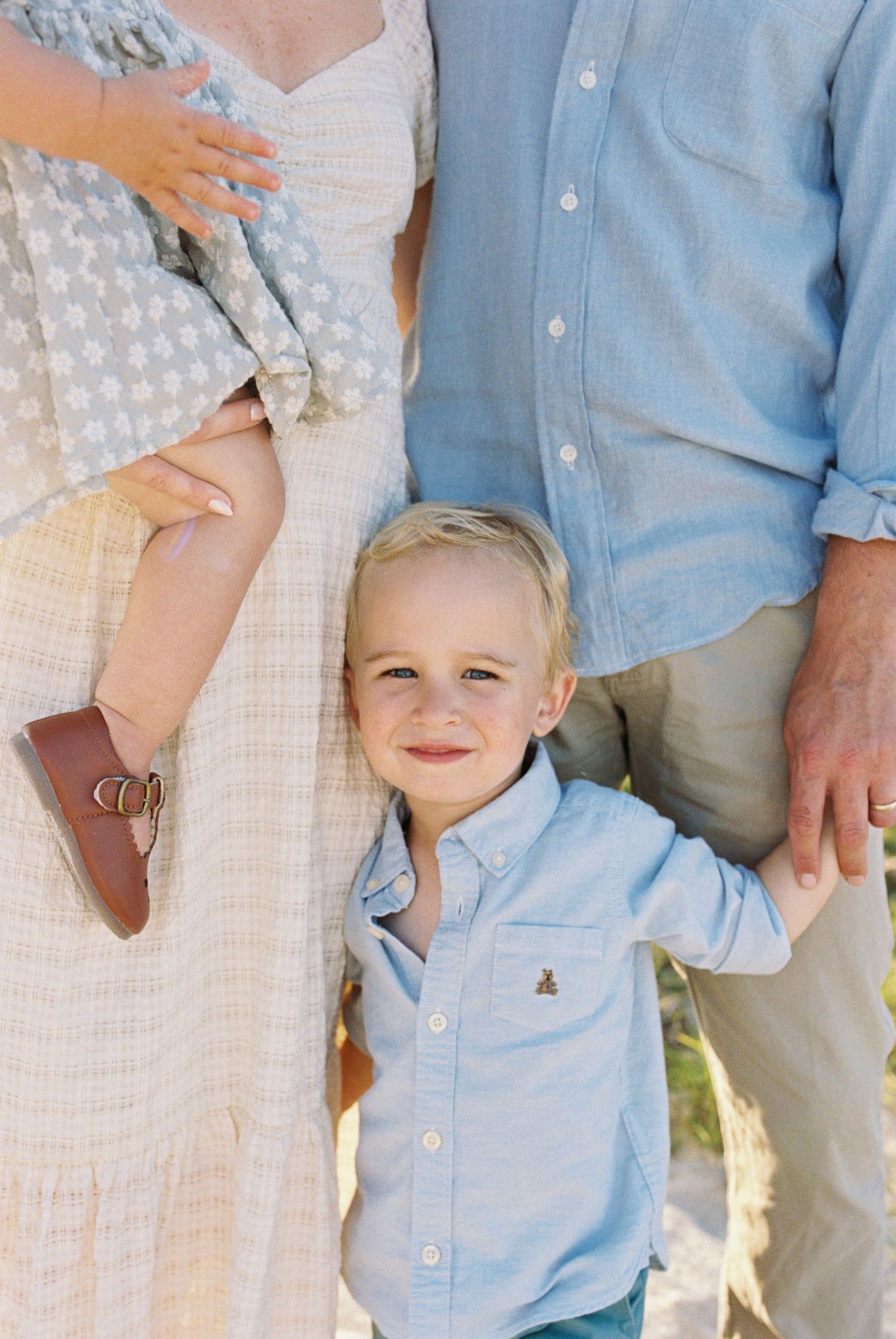 Family dressed in coordinating blue and white outfits on beach.
