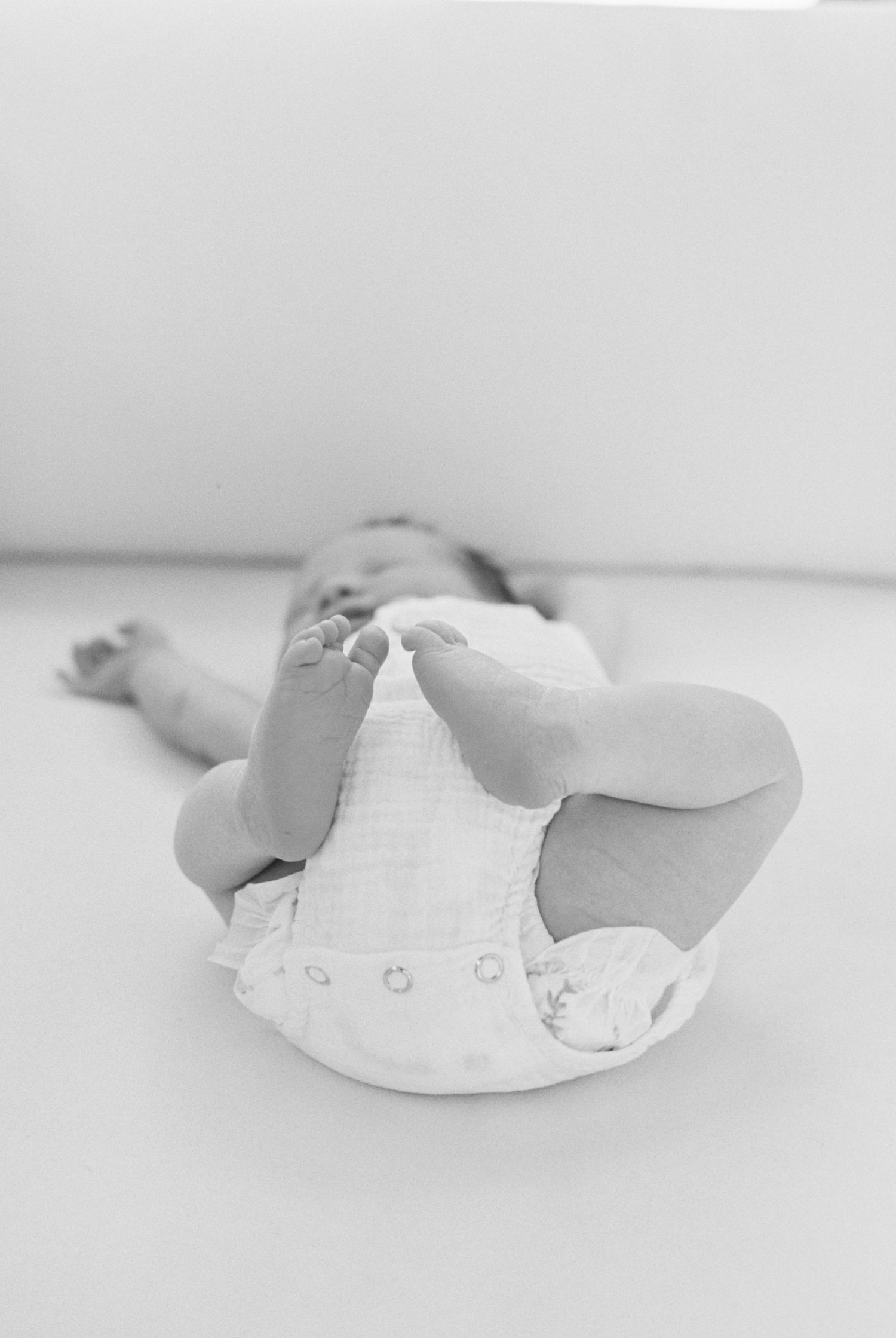 Side view of sleeping newborn baby wearing white outfit.