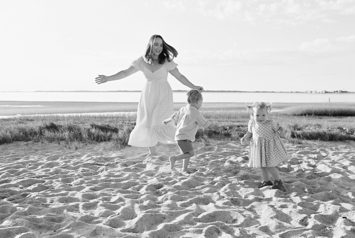 People enjoying a carefree moment on a sandy beach with marsh grass in the background.