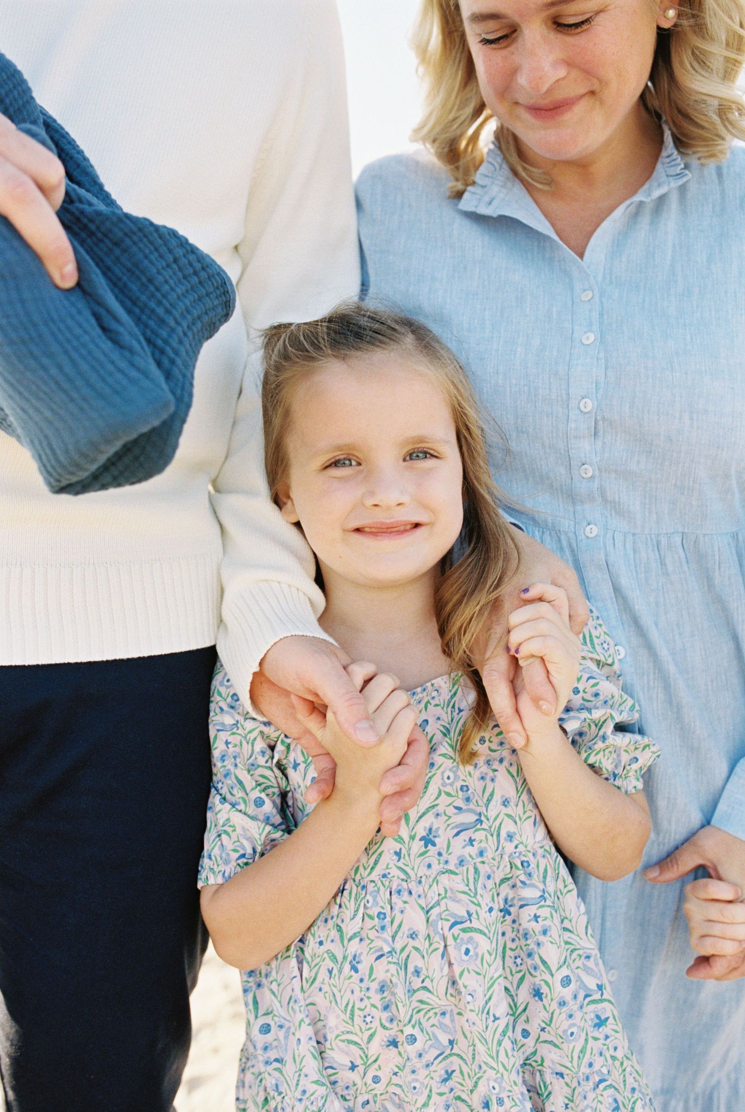 Family portrait showing tender moments in soft blue and floral outfits.