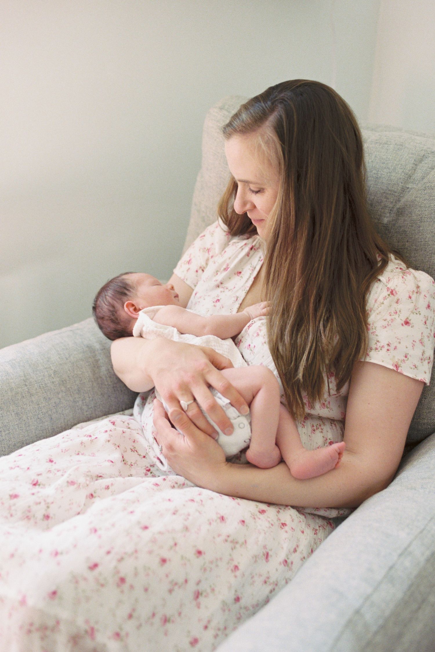 A tender moment of mother and newborn bonding in a cozy armchair.