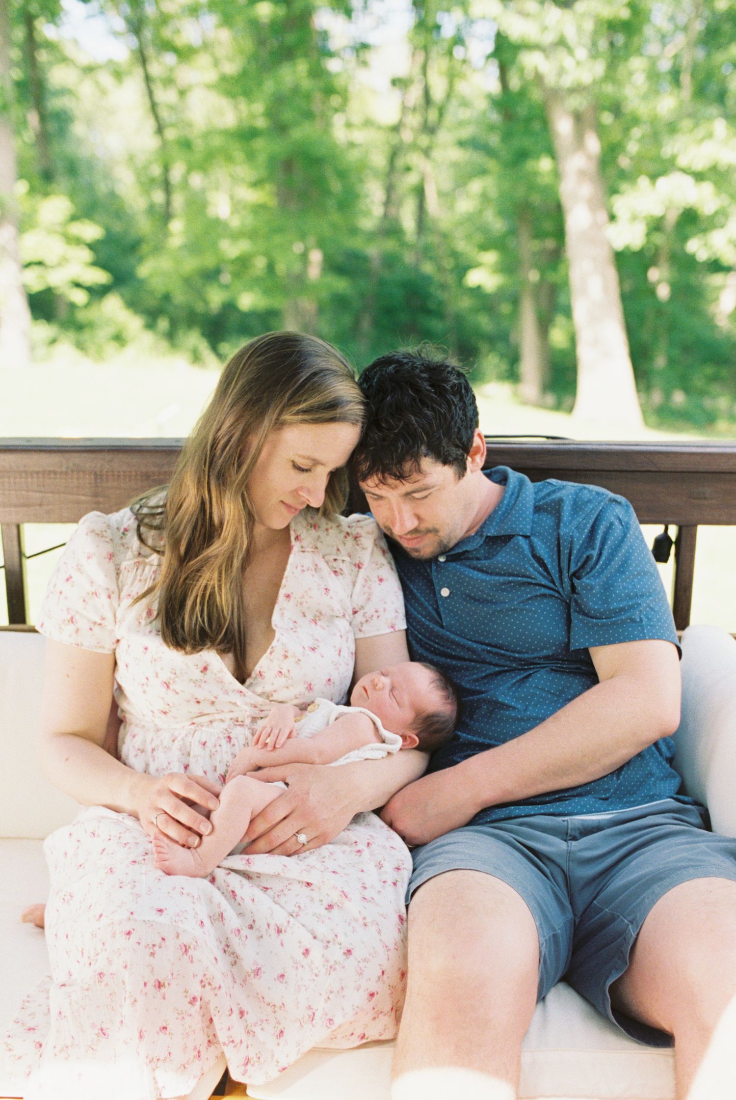 Family sharing tender moment with newborn on outdoor deck.